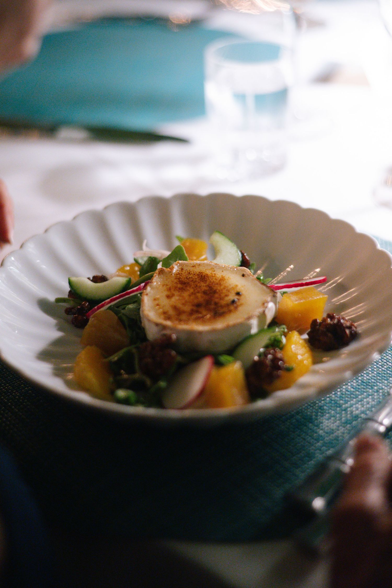 Elegant plated dish with scallops and microgreens served on white china at an upscale restaurant.