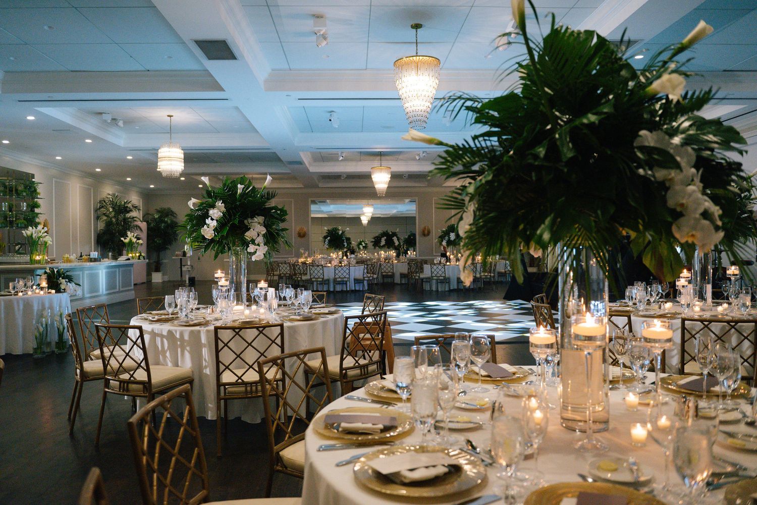 Sophisticated wedding reception hall with crystal chandeliers and elegantly set dining tables.