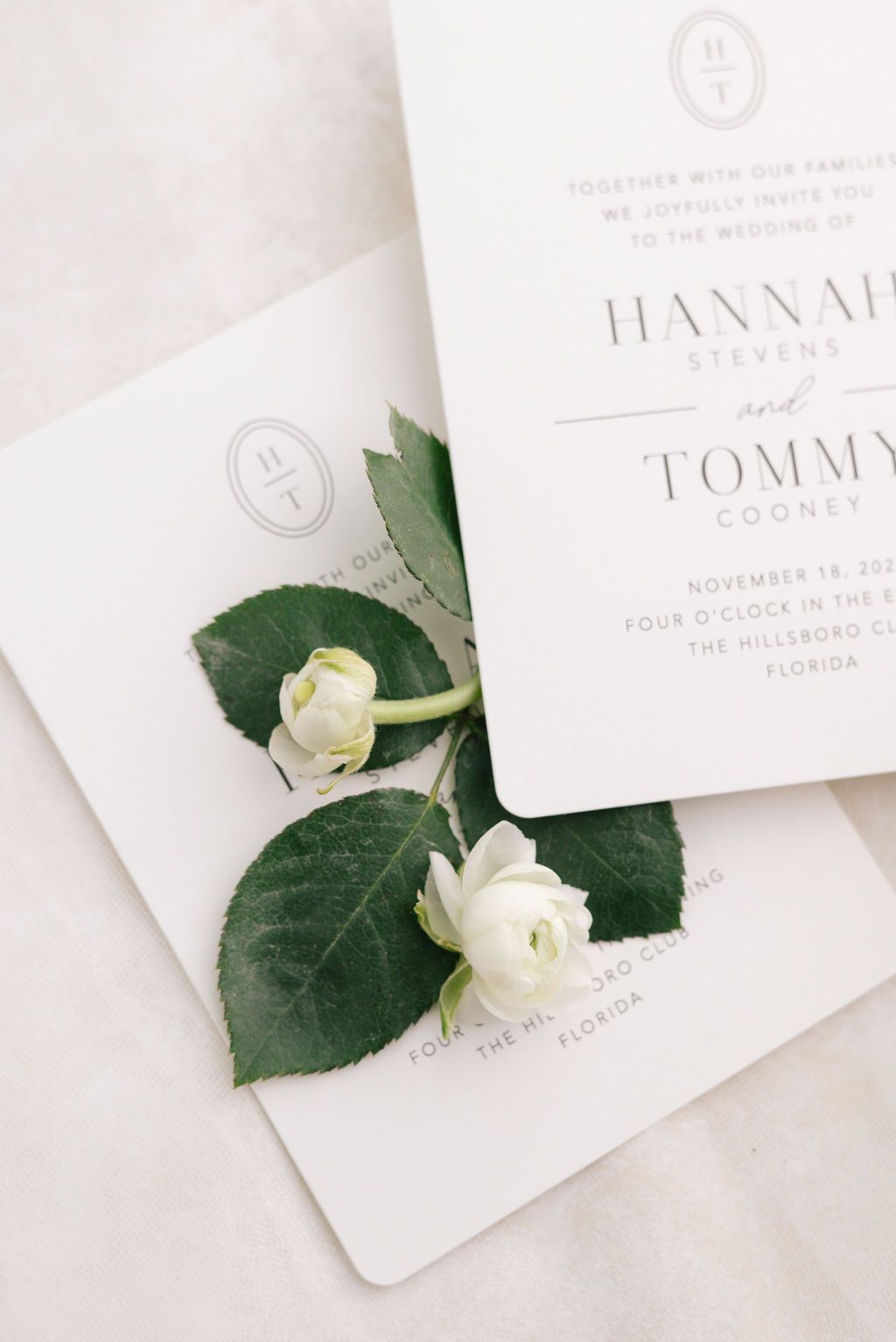 Minimalist wedding invitation with white floral accents and elegant typography.