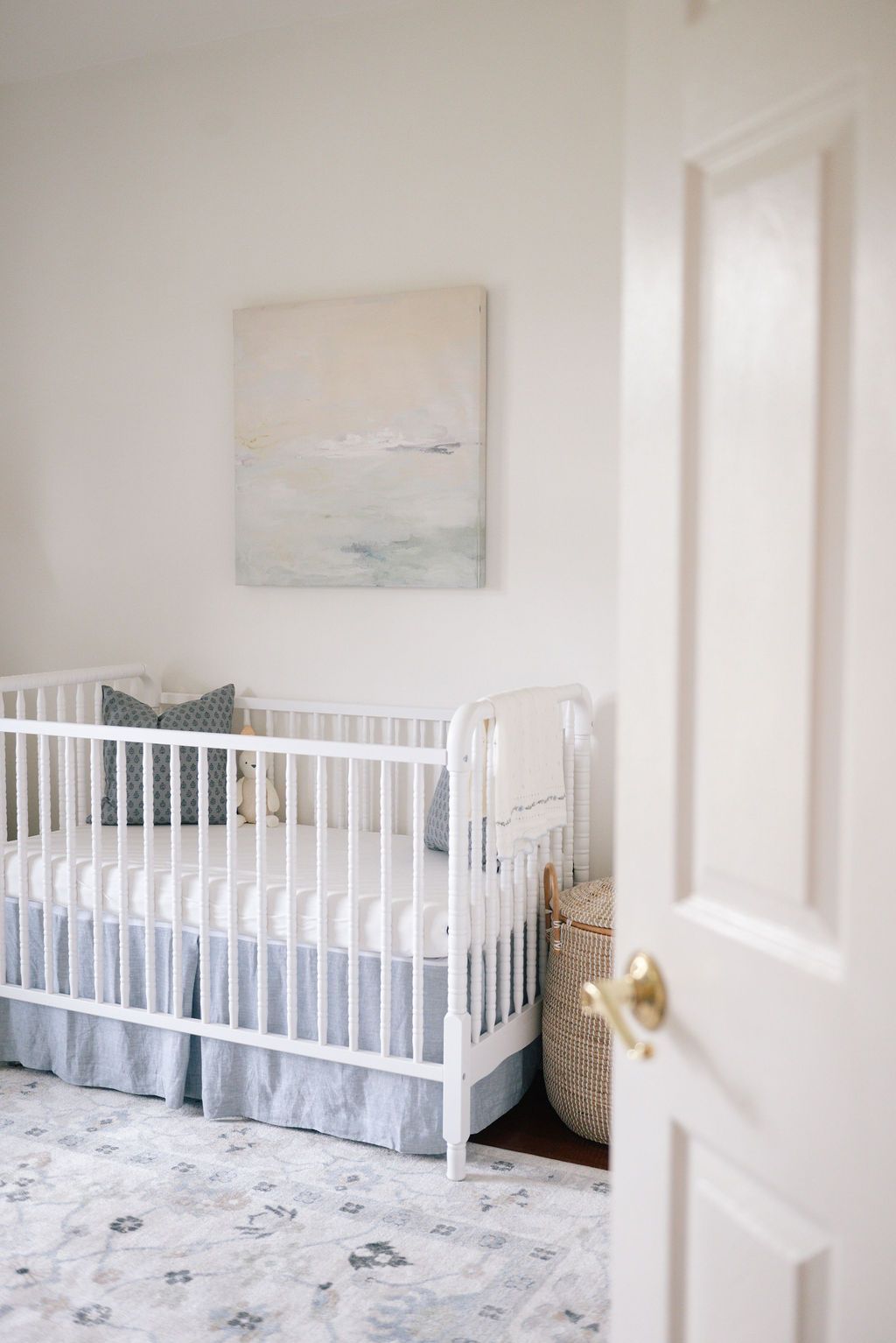 Modern white nursery featuring crisp white crib, blue accents, and minimalist wall art.