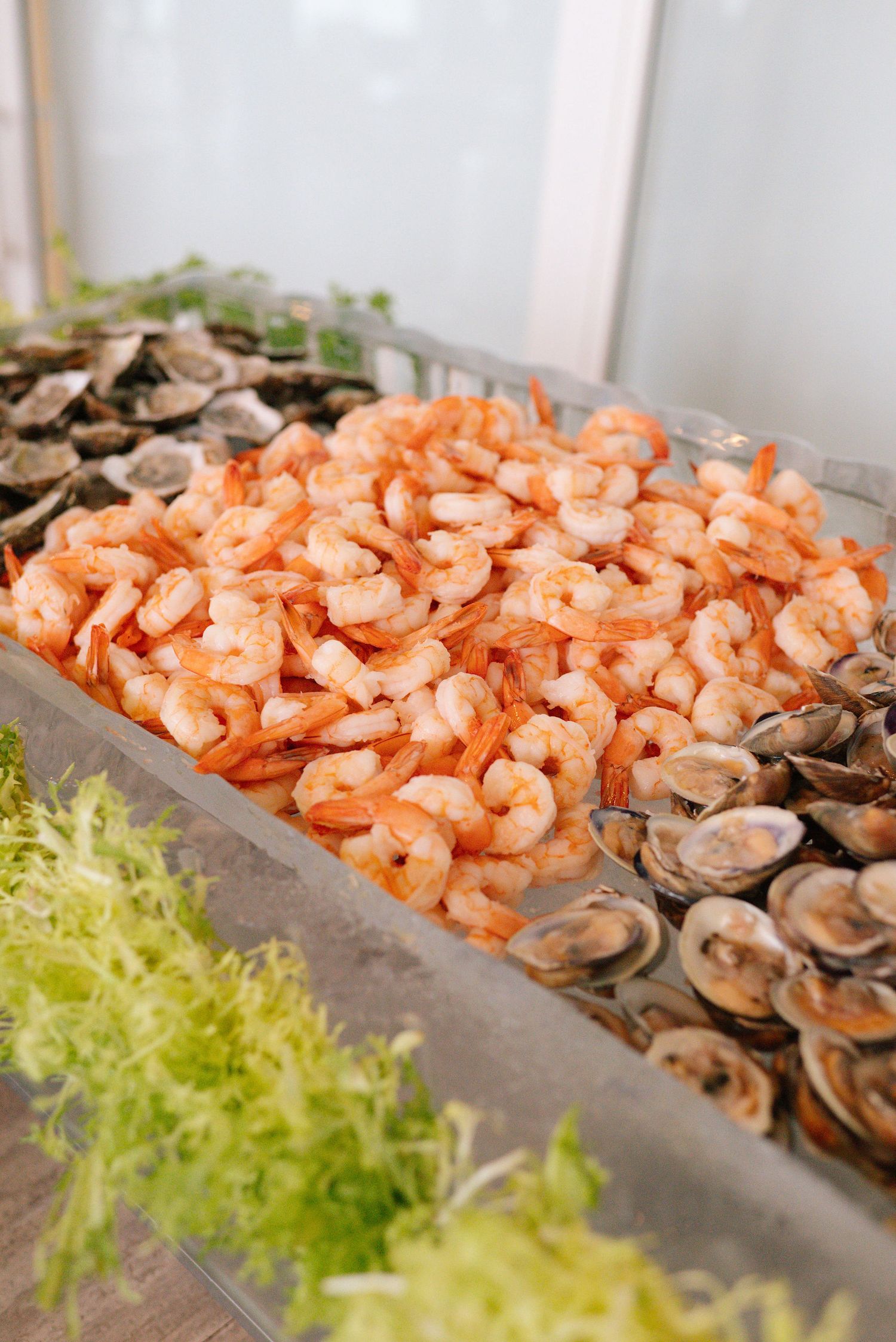 Fresh seafood display featuring shrimp and oysters with garnish at wedding reception.