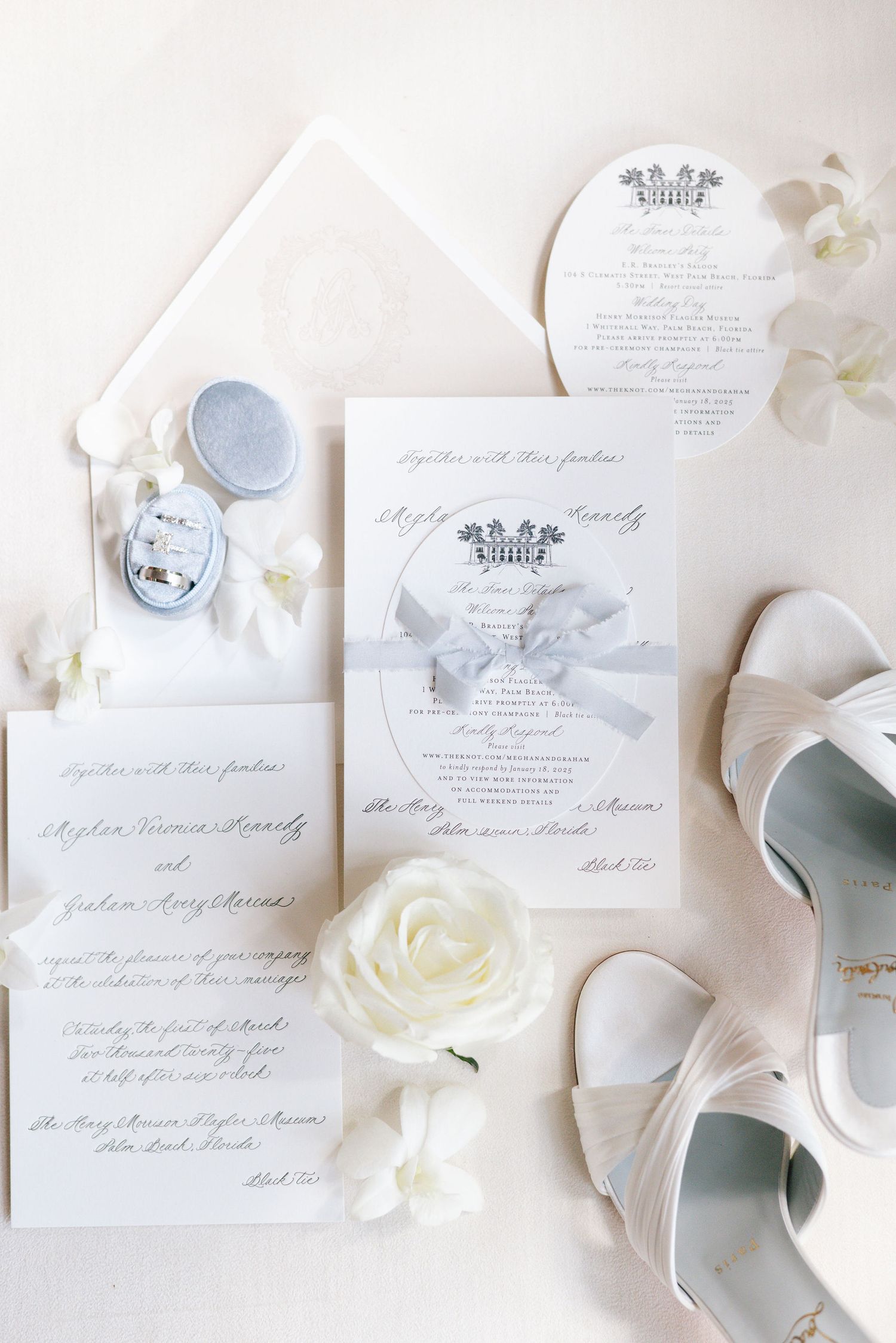 Wedding stationery flat lay featuring invitations, white rose, bridal shoes and delicate details.