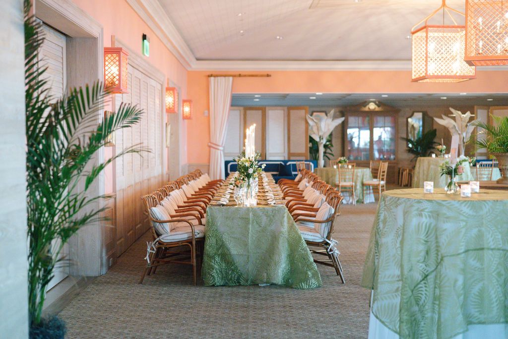 Coastal dining room with sage green tablecloths and coral walls set for an event.
