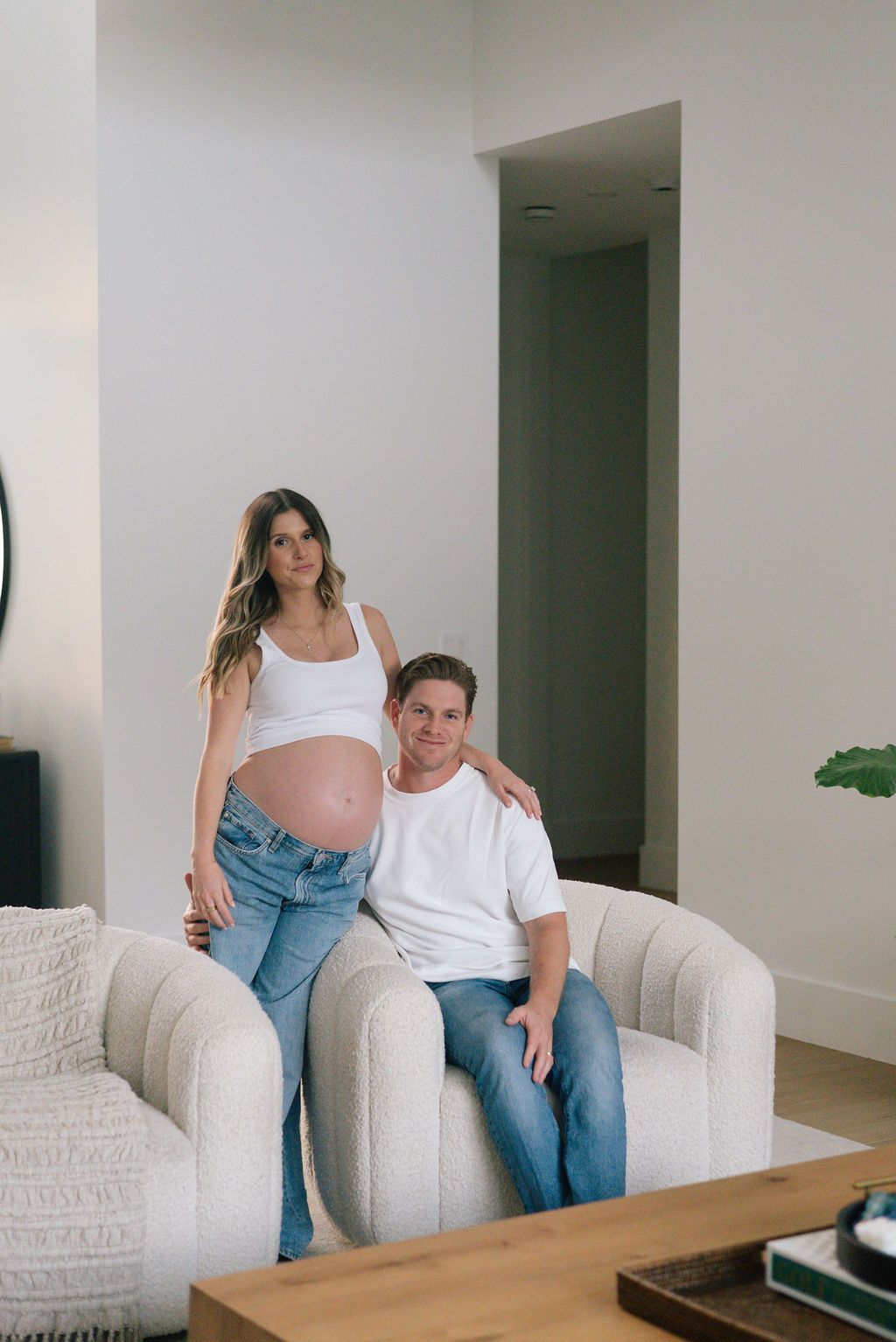 Candid moments of a couple lounging on a white textured sofa with houseplants in background.