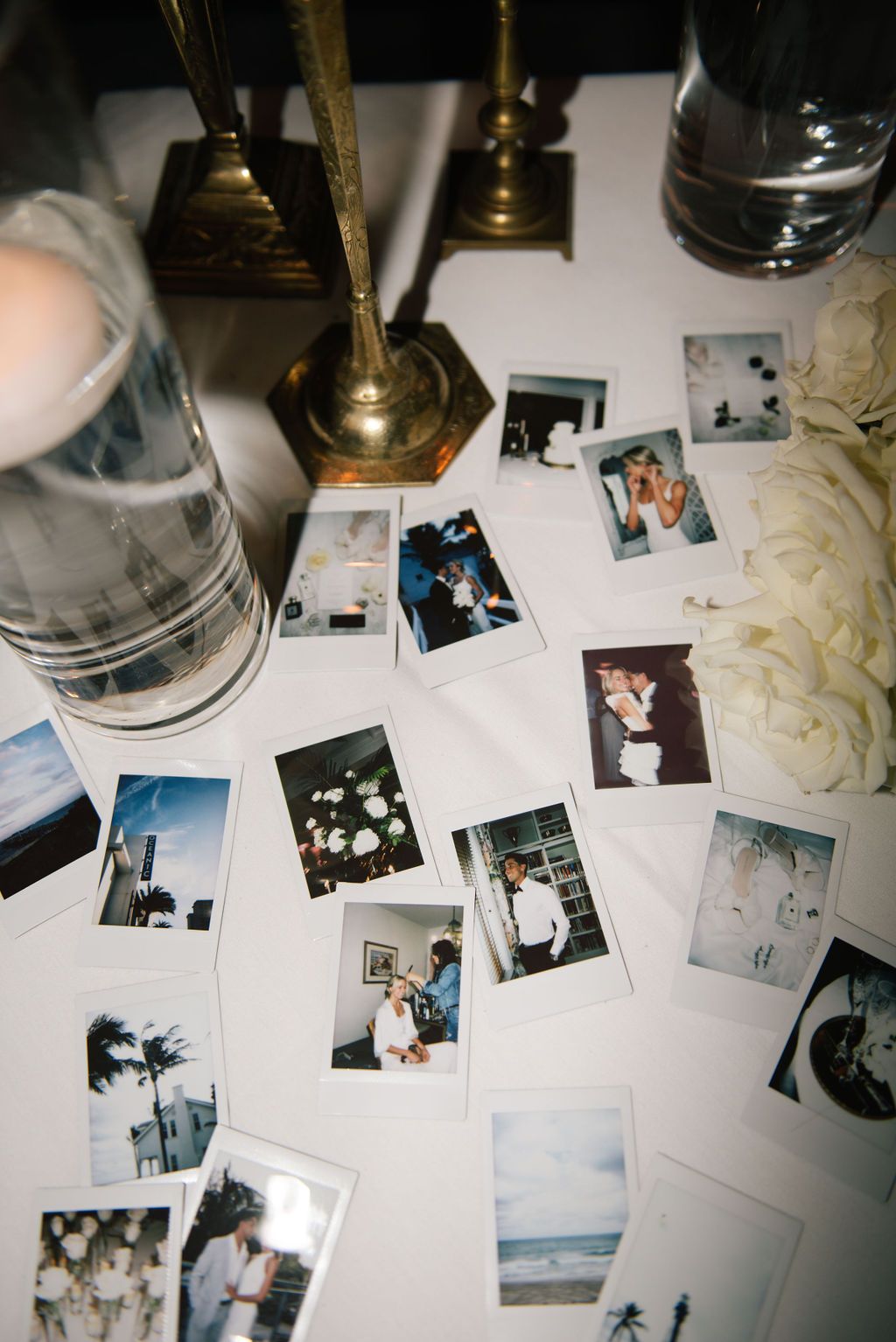 Collection of polaroid photos scattered on a white tablecloth at a wedding reception.