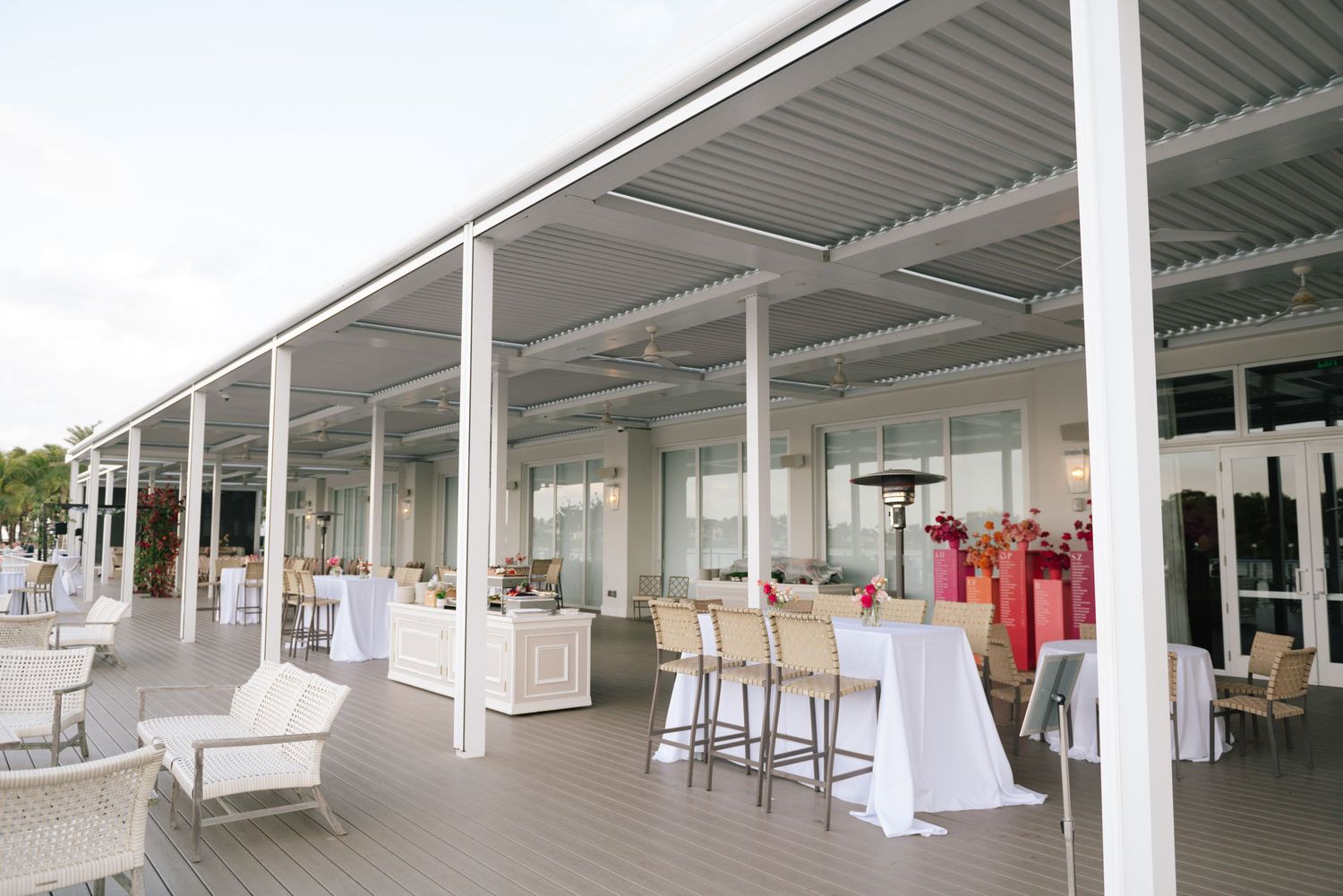 Modern white covered patio area set up for an event with bar stools and lounge furniture.