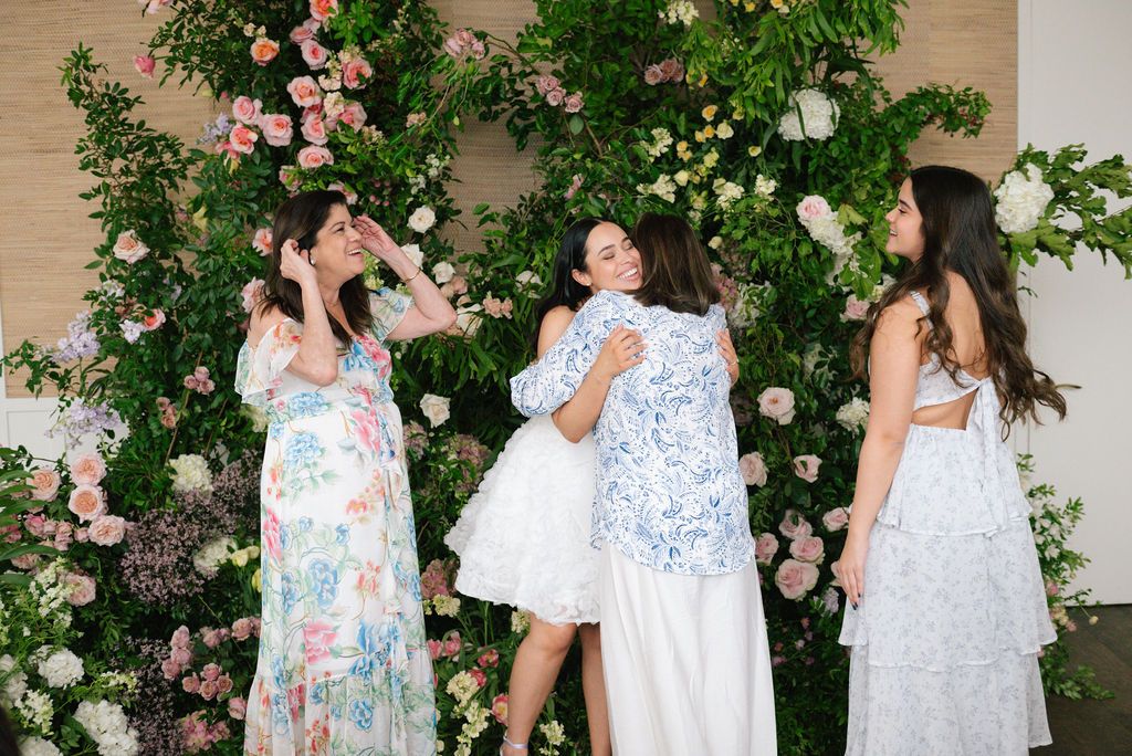 Group wearing coordinated floral and white outfits posing against a garden backdrop.