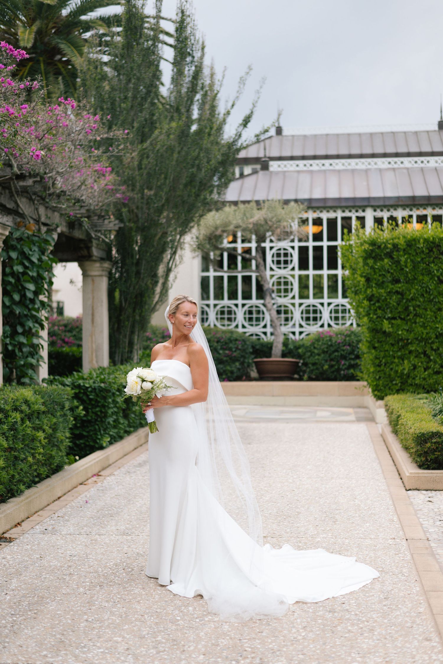 Bridal portraits on a white gravel path with blooming bougainvillea and modern architecture.
