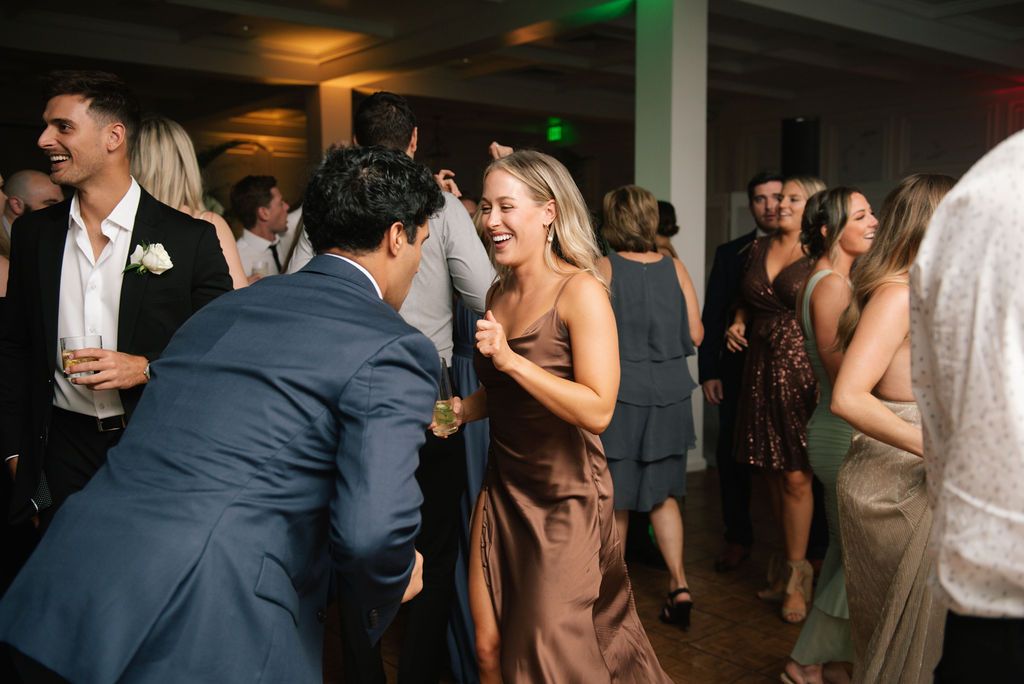 Wedding guests laugh and dance together during the reception party.