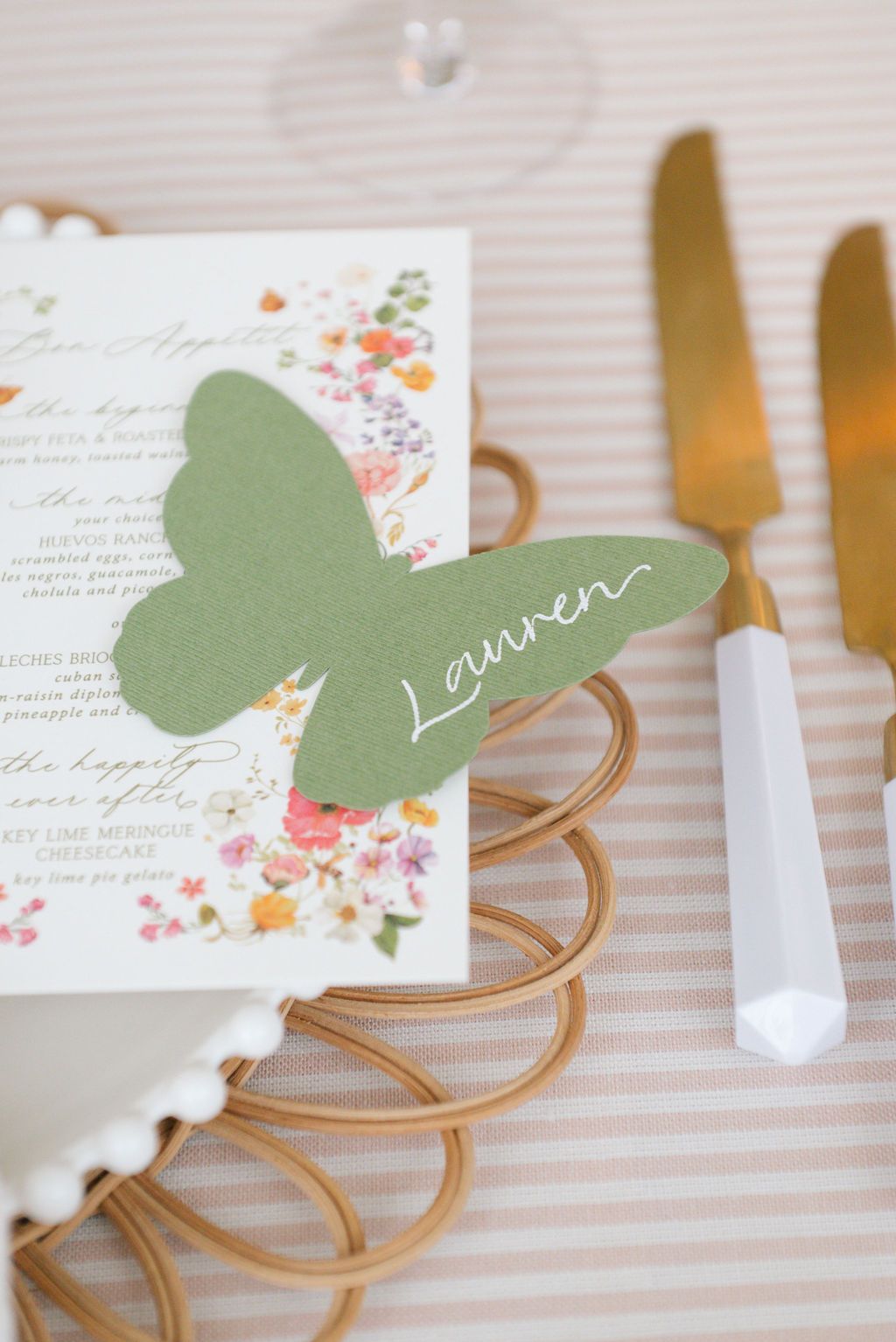 Place cards with sage green butterfly accents displayed on gold wire holders.
