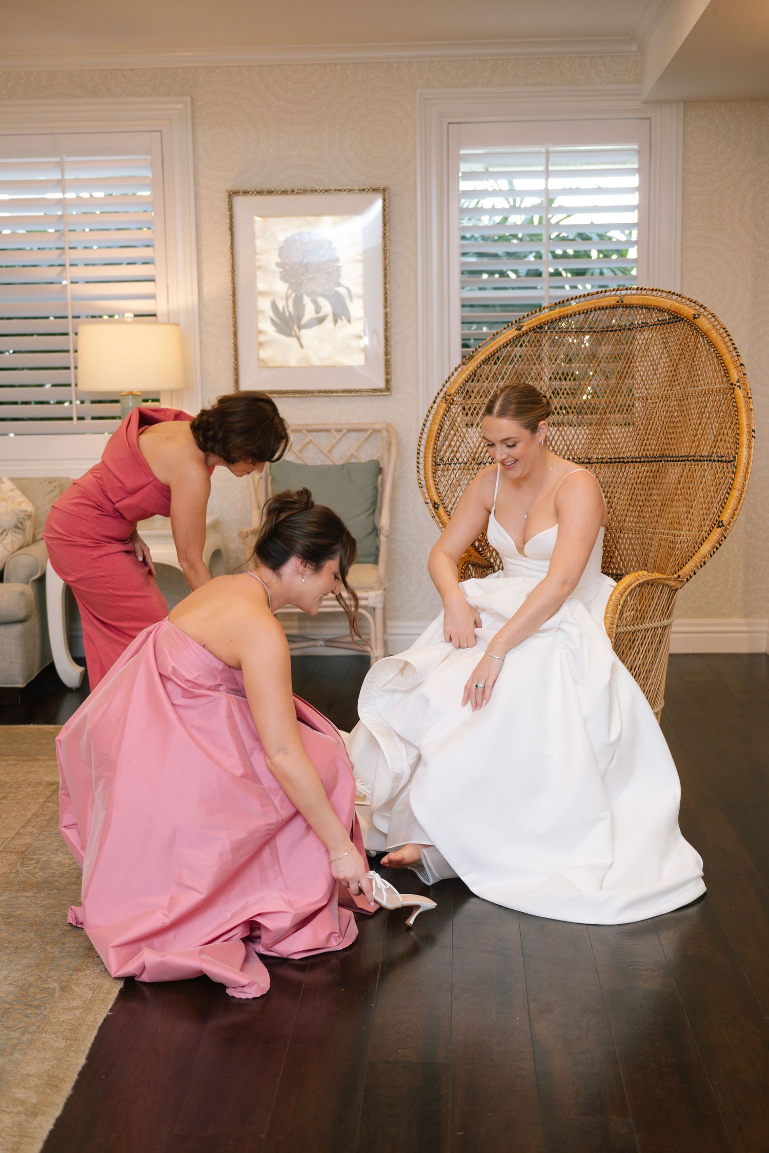 A series of photos showing someone in a pink dress helping adjust a white wedding gown indoors.