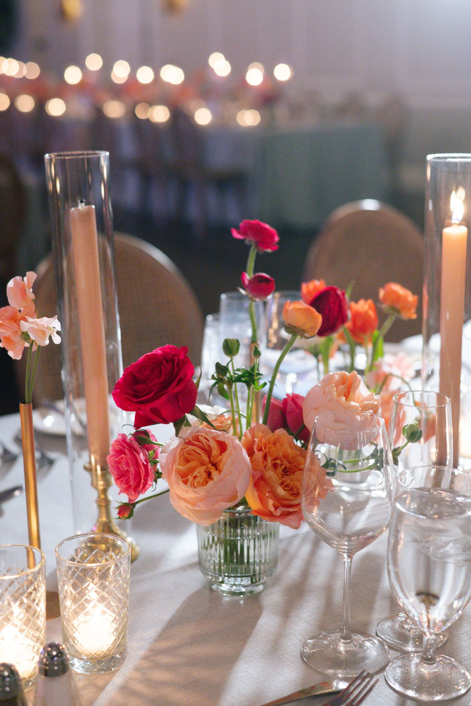 Elegant table setting with pink and red roses, candles and wine glasses.