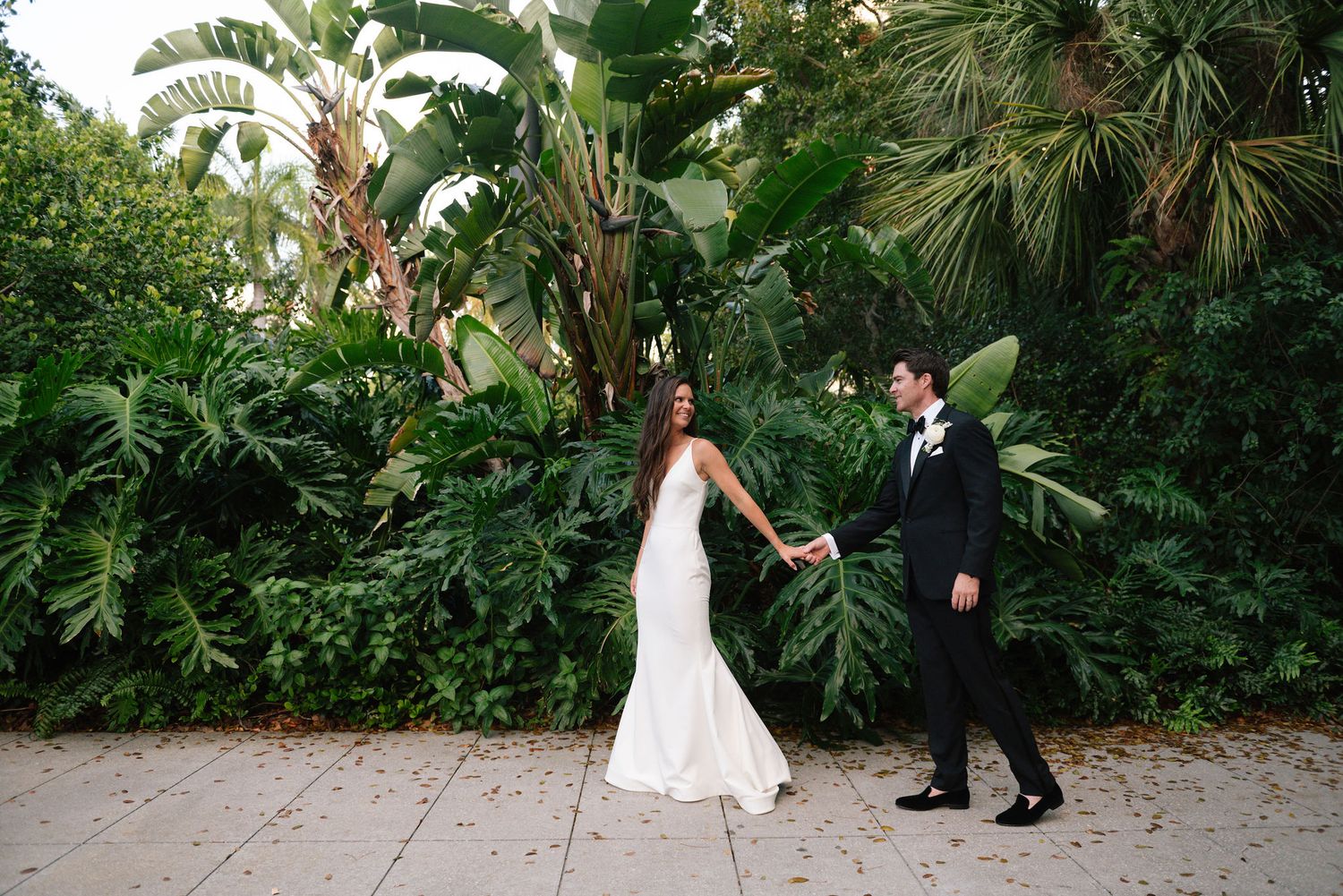 Couple walking through a lush tropical garden pathway during their wedding.