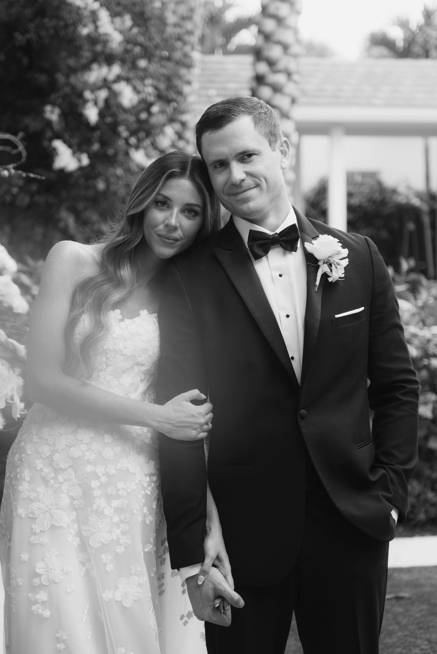 A romantic black and white portrait of a couple in formal wedding attire.