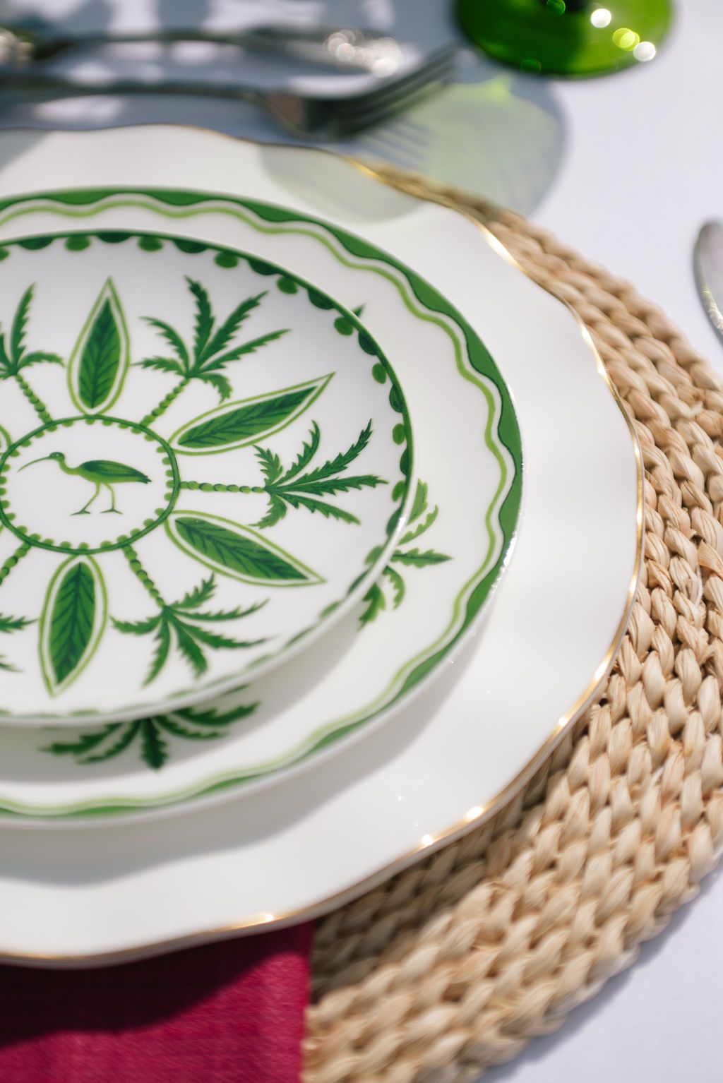 Decorative white plates with green botanical patterns on woven placemats.