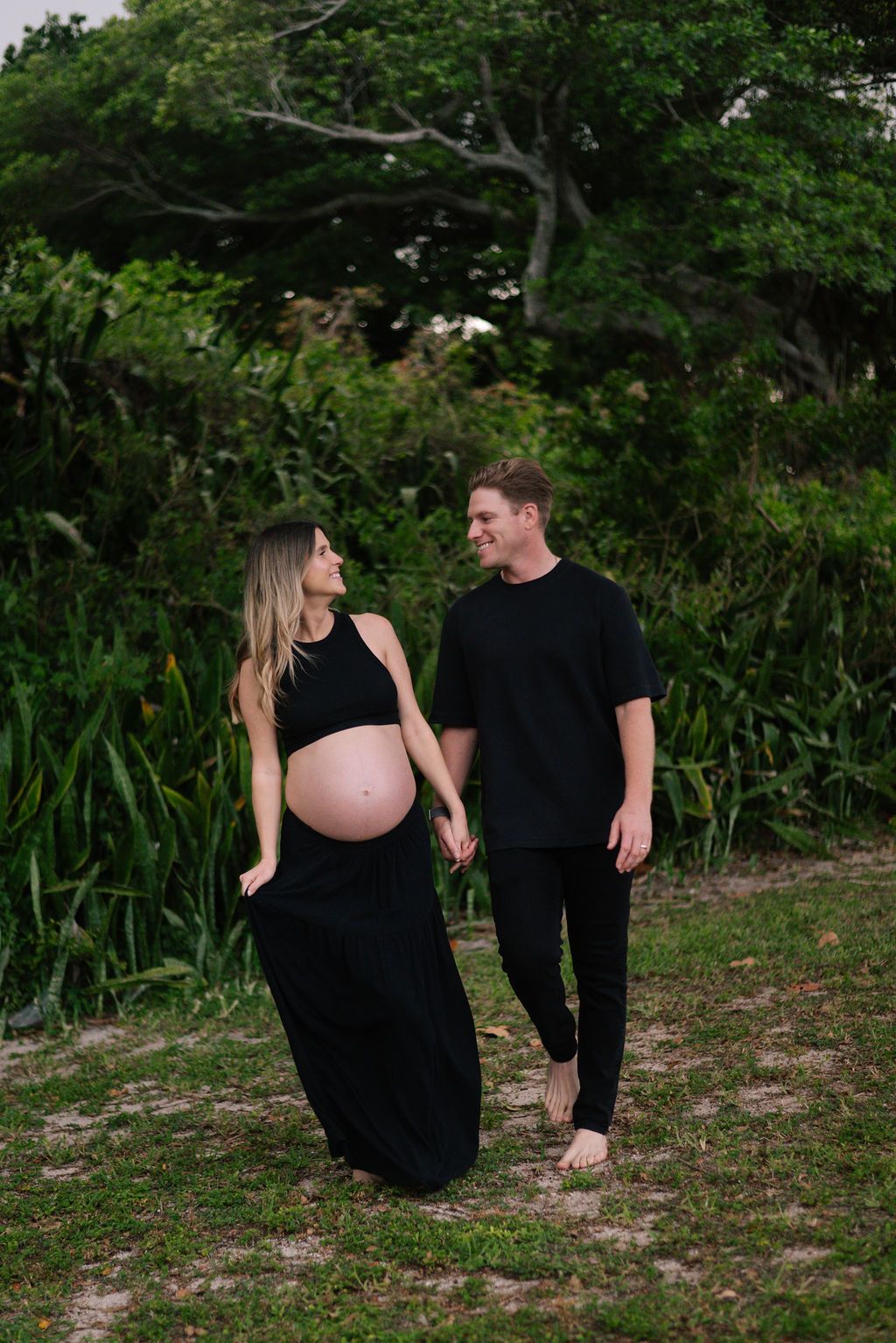 Expectant couple sharing intimate moments during outdoor maternity photoshoot.