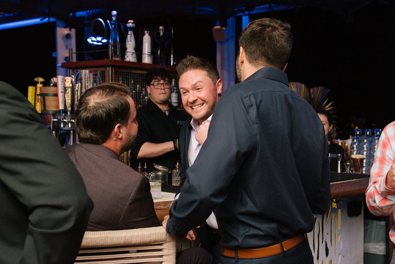 Casual conversation between guests at a dimly lit bar counter.