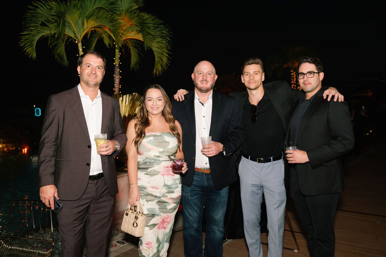 Group photo of party guests at a nighttime outdoor celebration.