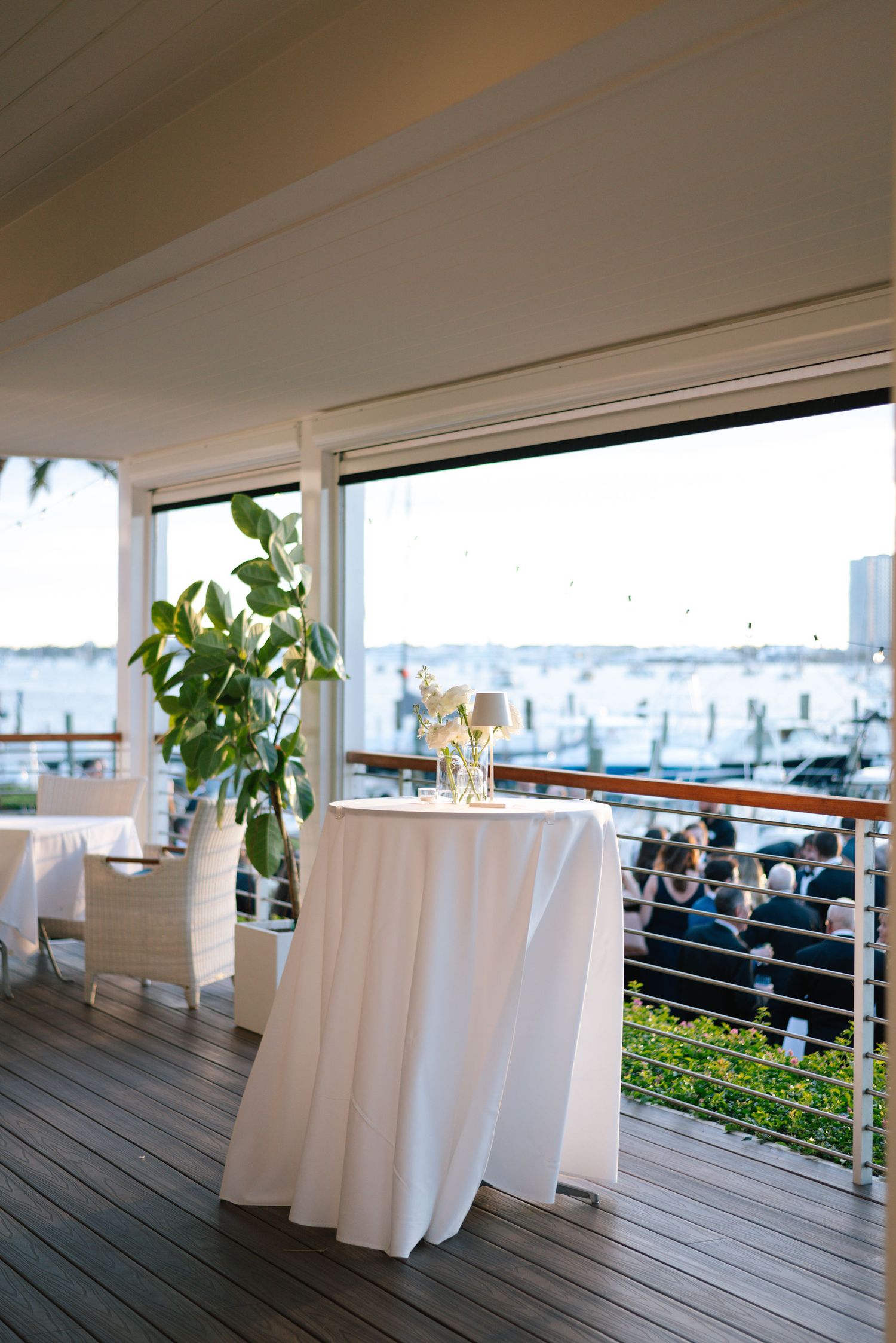 White tablecloths line a waterfront deck venue with ocean views through large windows.