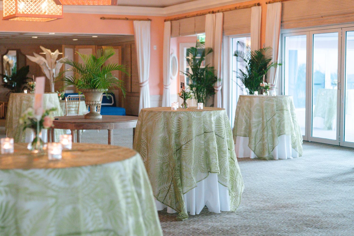 Elegant banquet hall interior with white draped tables, peach walls, and large windows creating a warm atmosphere.