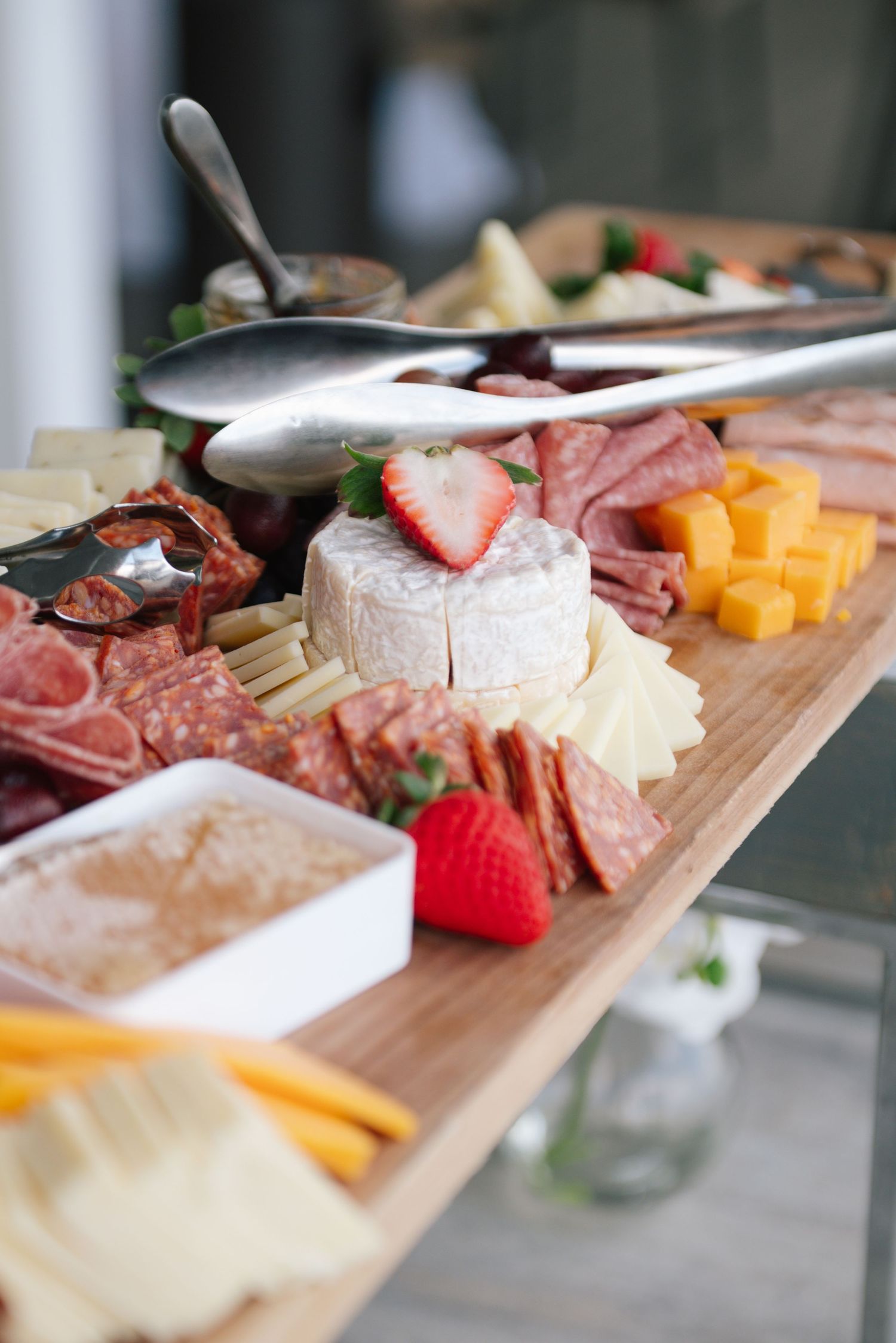 Artfully arranged charcuterie board with meats, cheeses, and fresh strawberries.