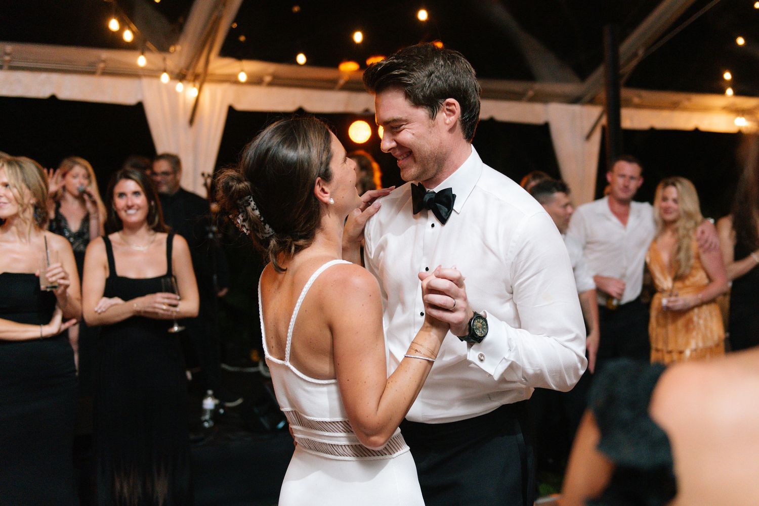 Wedding reception dance floor with guests celebrating under ambient lighting.