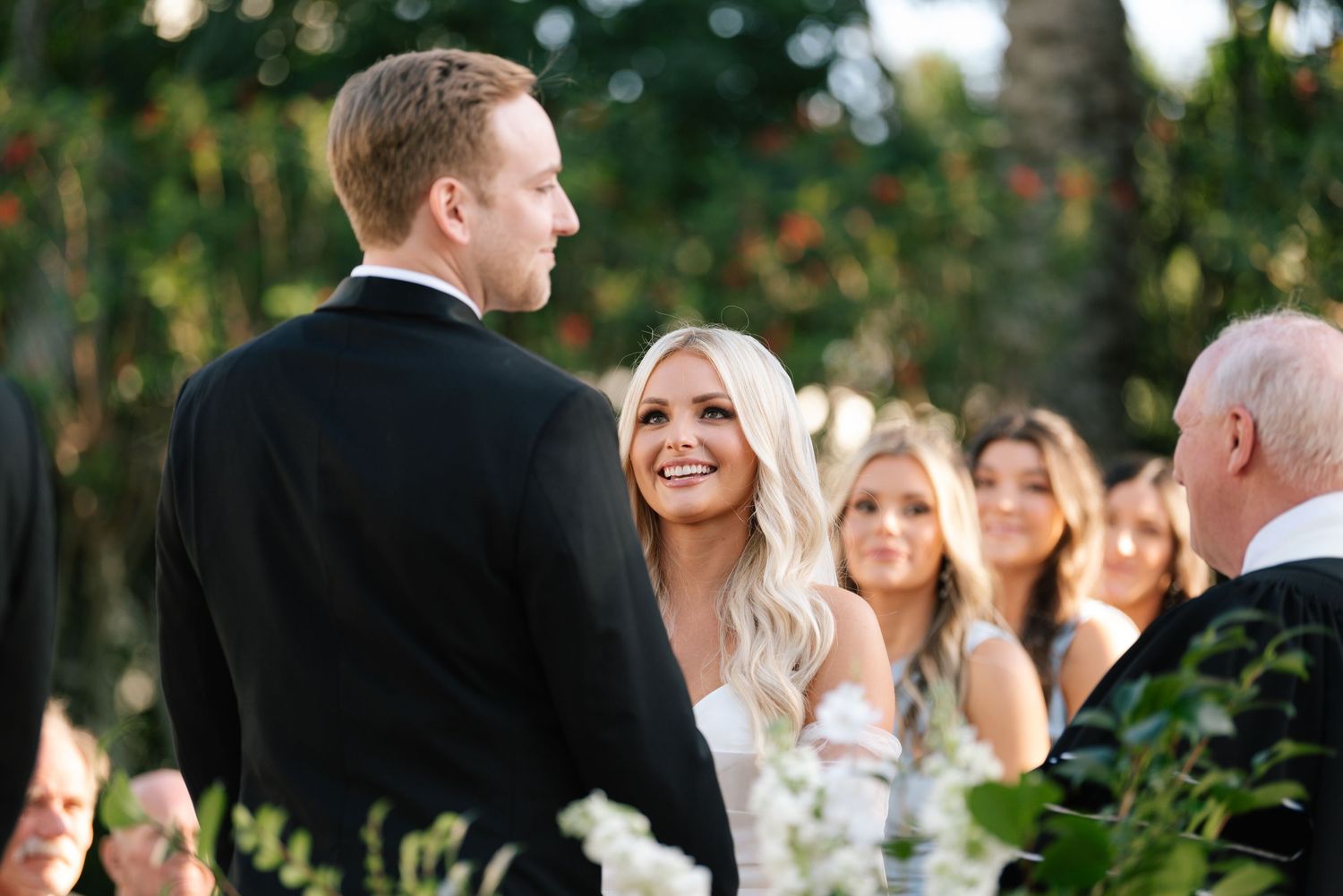 Wedding ceremony guests gather outdoors under natural lighting during celebration.