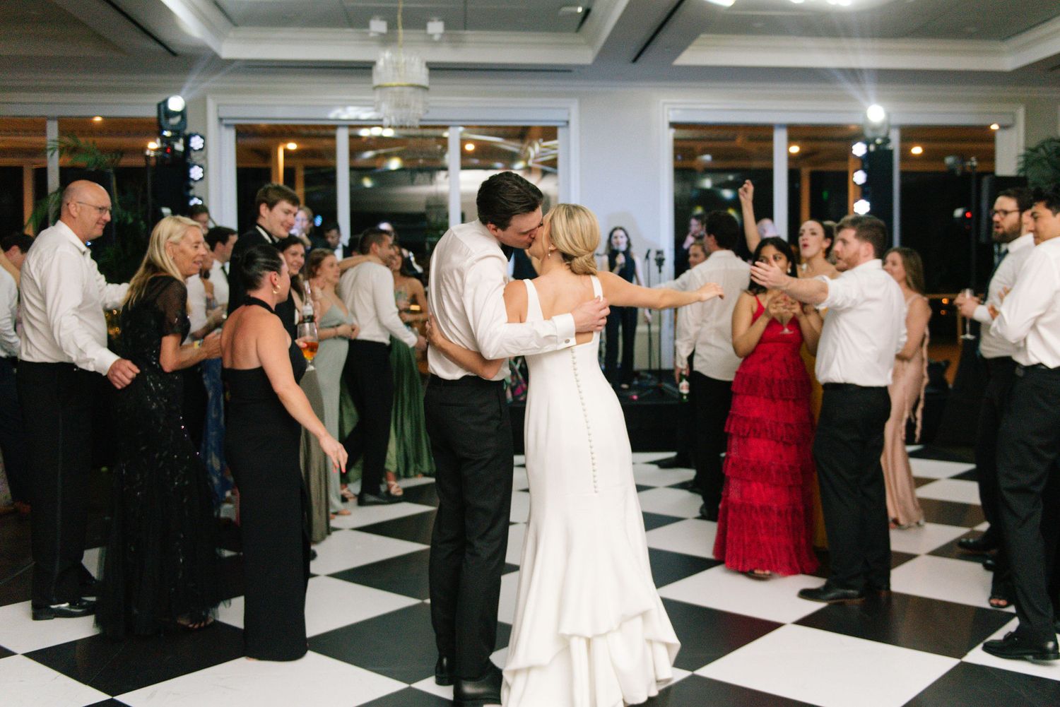 Lively wedding reception with guests dancing on a geometric black and white floor.