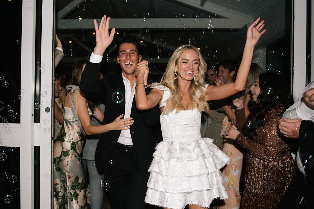Wedding guests dance and celebrate with raised arms on the dance floor.