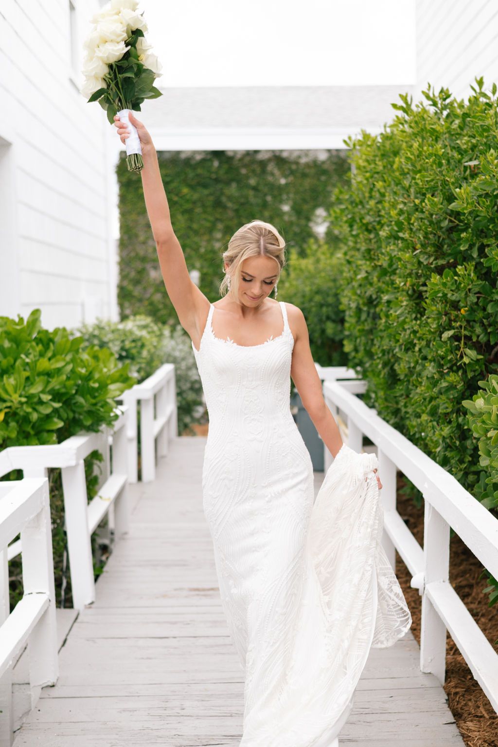 Joyful bride dancing and twirling on white boardwalk path.