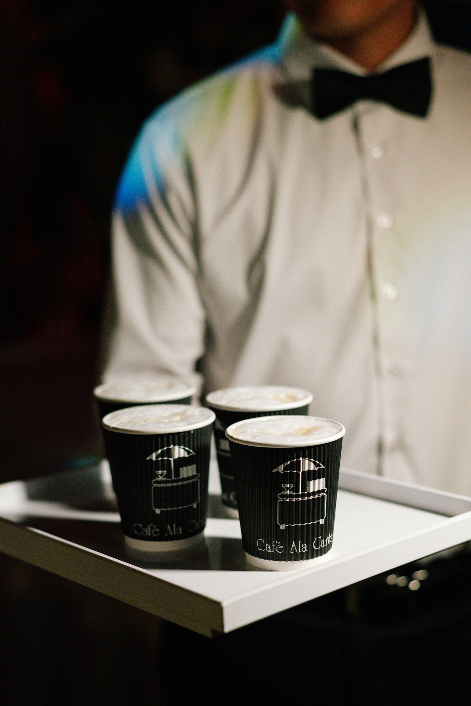 Black and white branded coffee cups arranged on a serving tray.