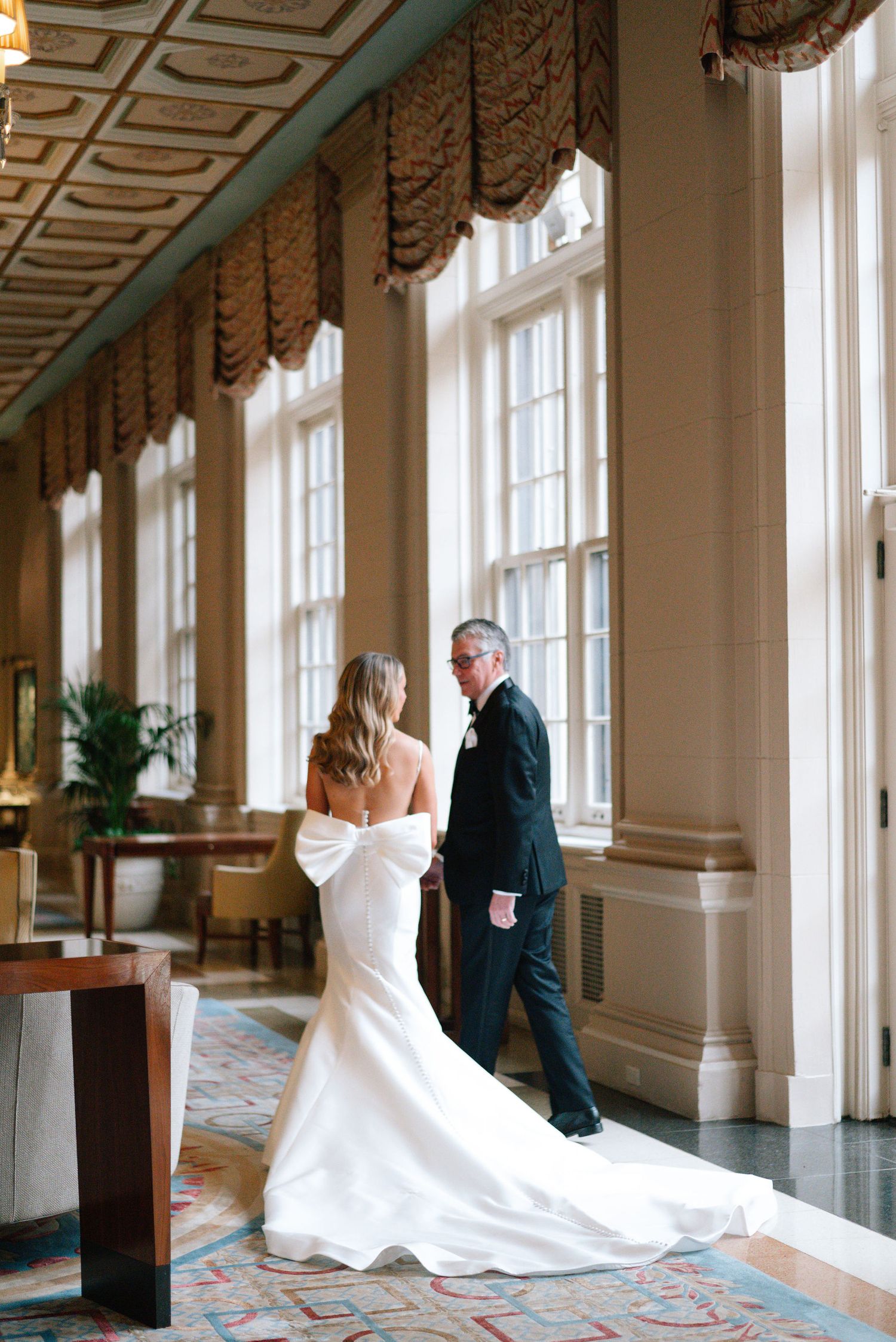 Interior hallway of luxury hotel with ornate ceiling and large windows creating dramatic lighting.