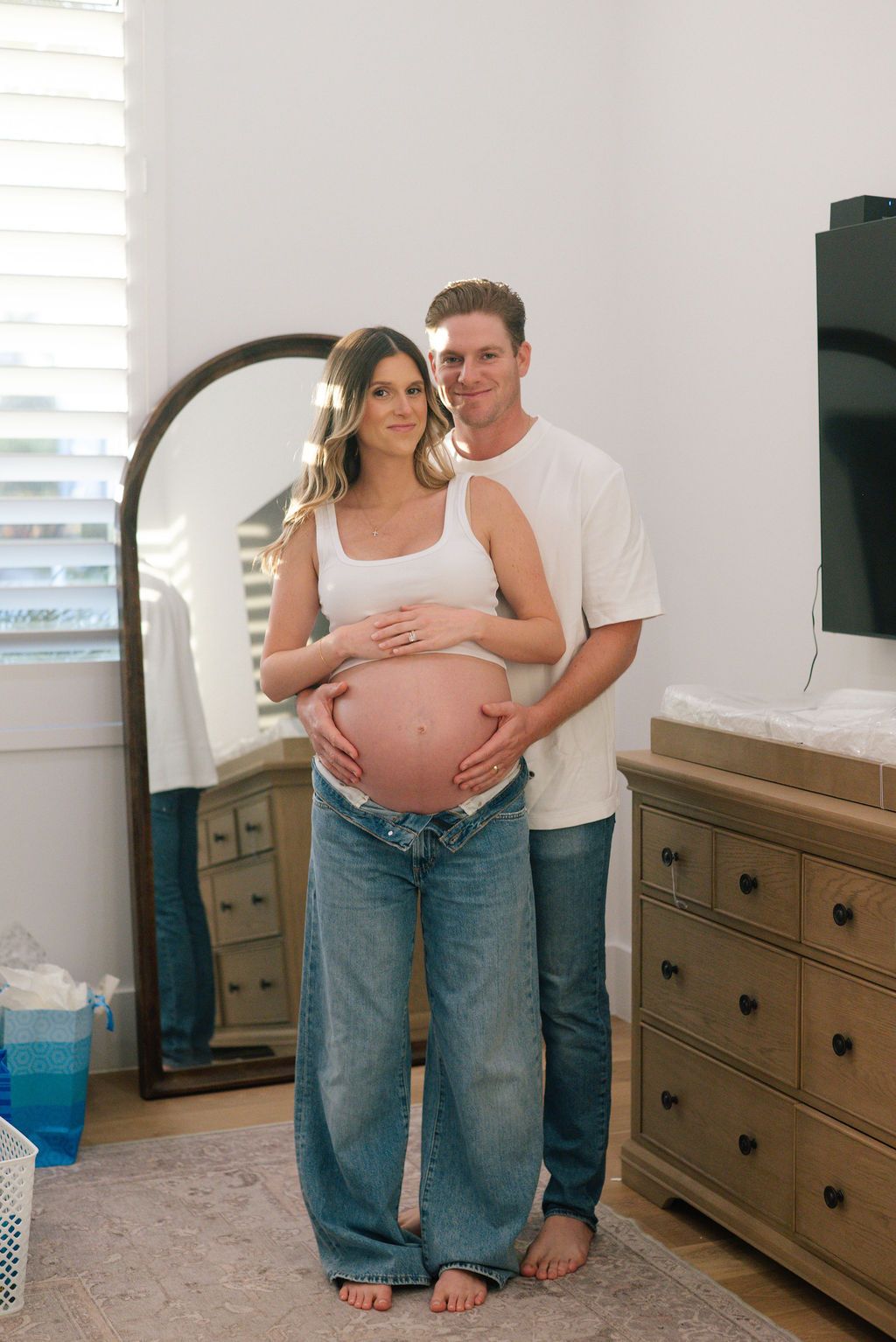 Couple in casual wear sharing tender moments in nursery with wooden furniture.