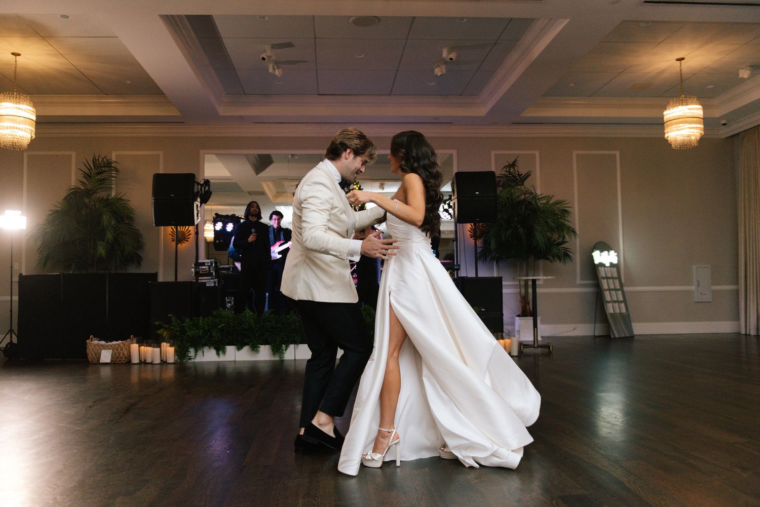 A couple performs a romantic dance move during their first dance at an elegant ballroom wedding reception.