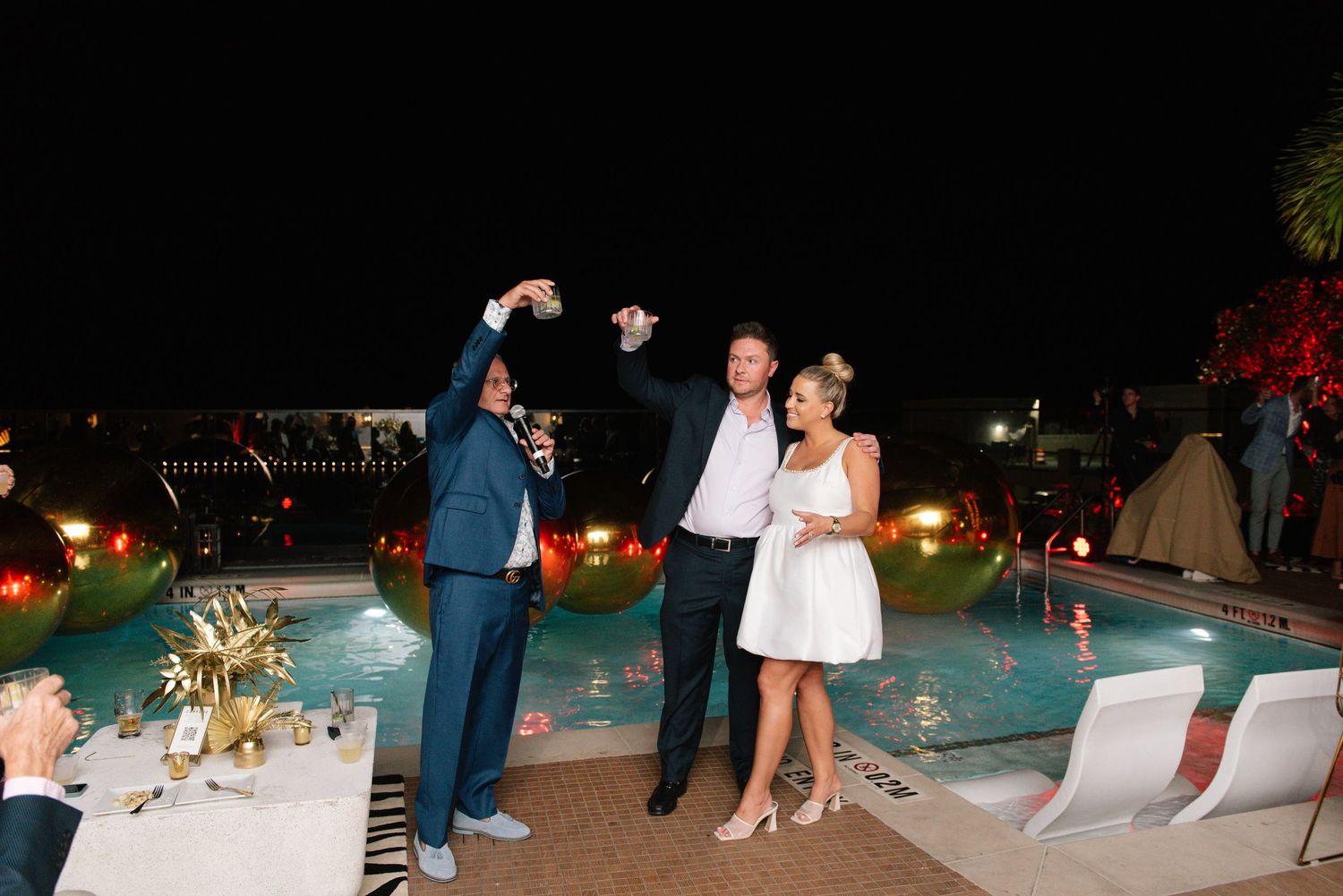 A celebratory moment by an illuminated pool during an evening event.