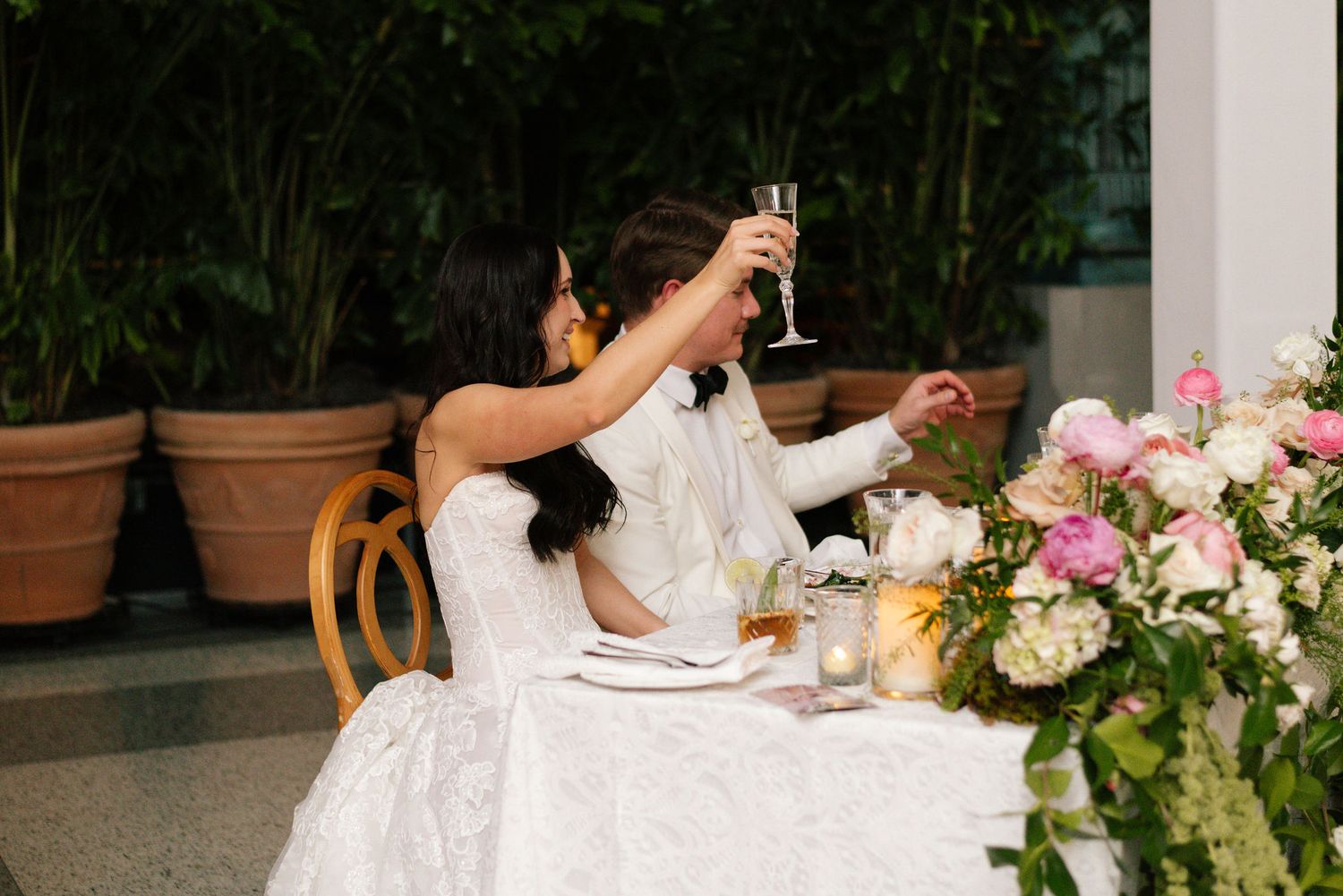 Wedding reception table decorated with elegant white floral arrangements and place settings.
