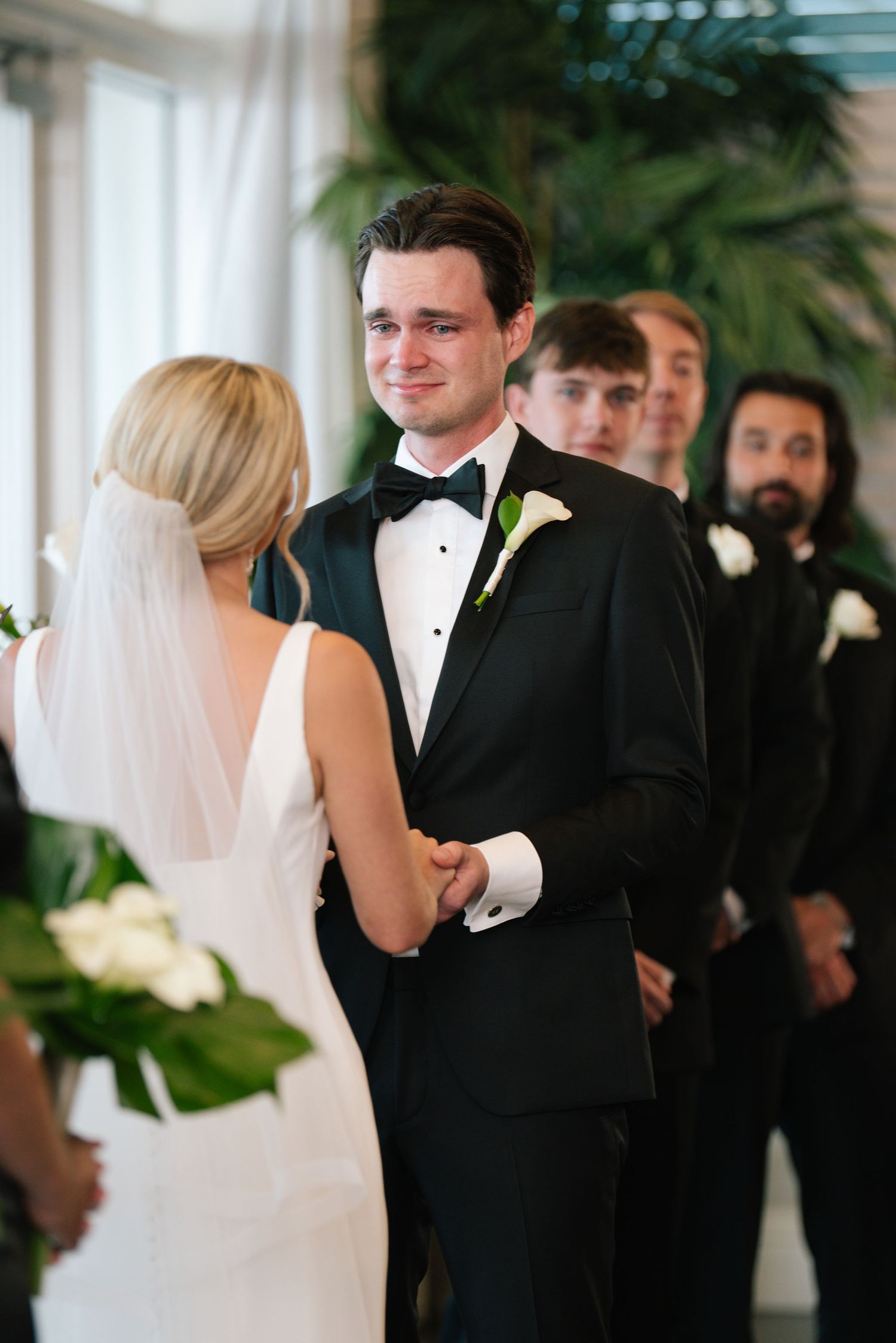 Intimate wedding ceremony moment with couple and groomsmen in classic black tuxedos.