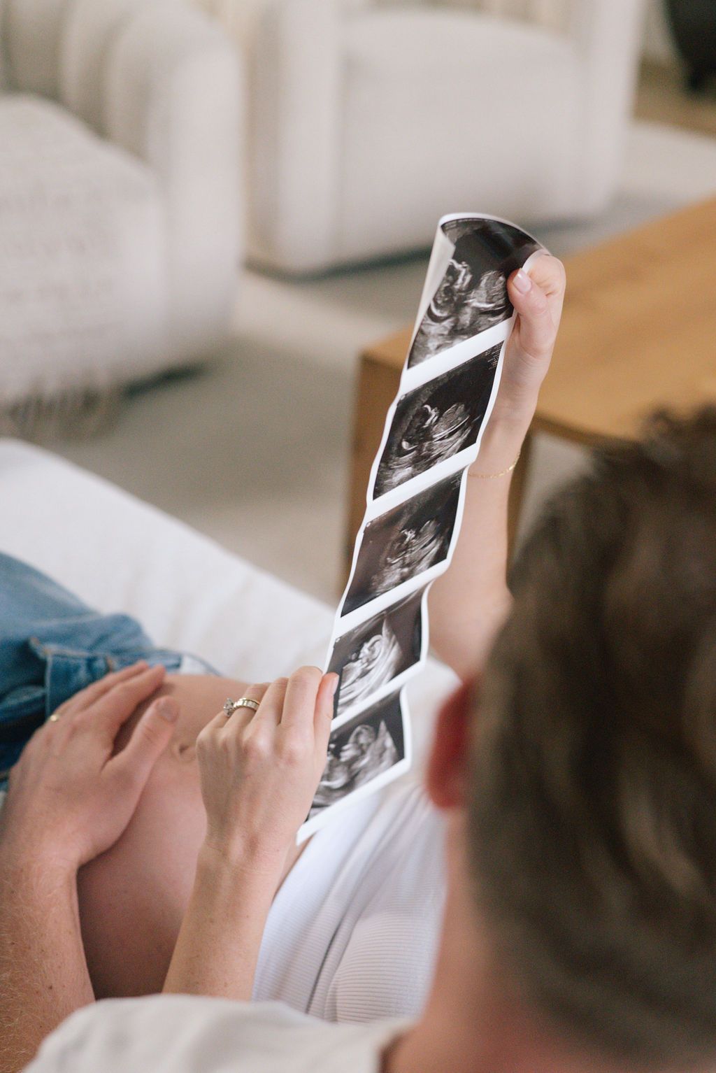 Close-up of hands holding ultrasound images during pregnancy announcement.