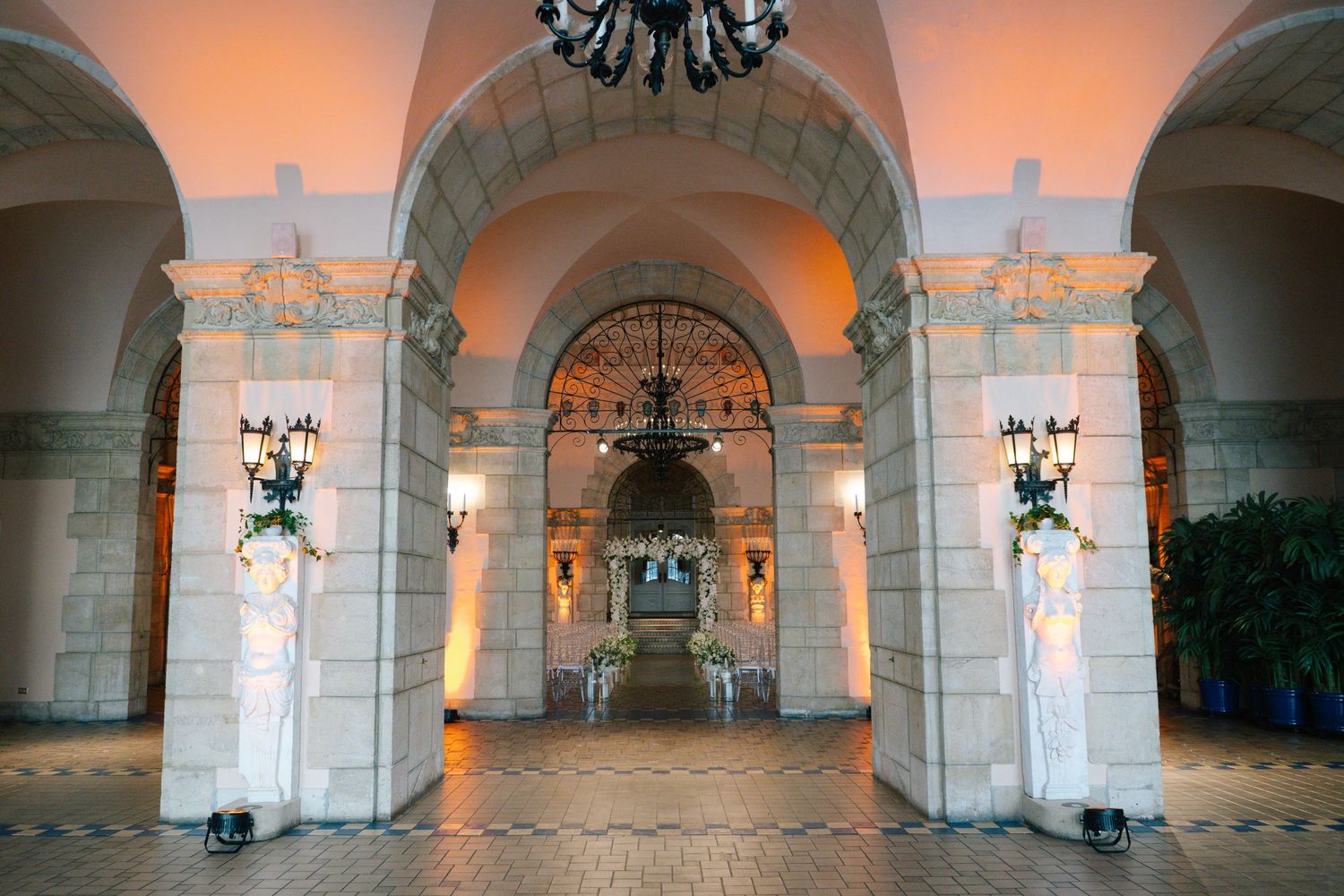 Elegant venue entrance with grand arches, ornate columns, and warm amber lighting perfect for weddings.