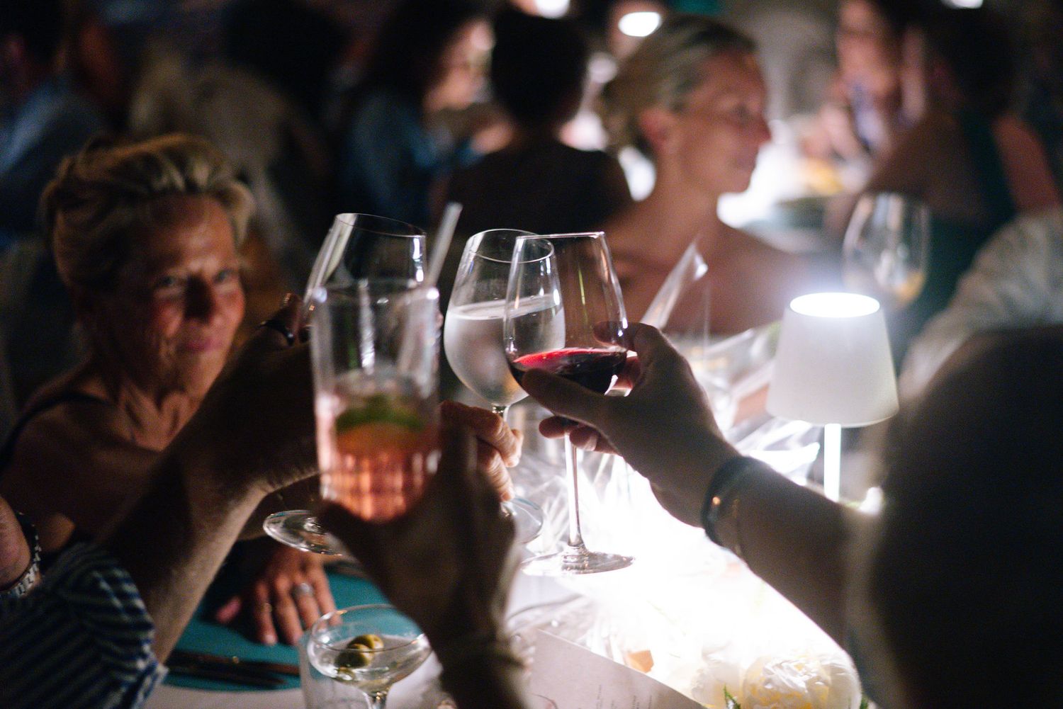 Dimly lit restaurant dining scene with wine glasses and ambient lighting.