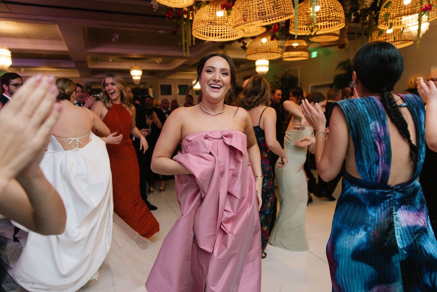 Wedding reception guests dancing and celebrating under crystal chandeliers.