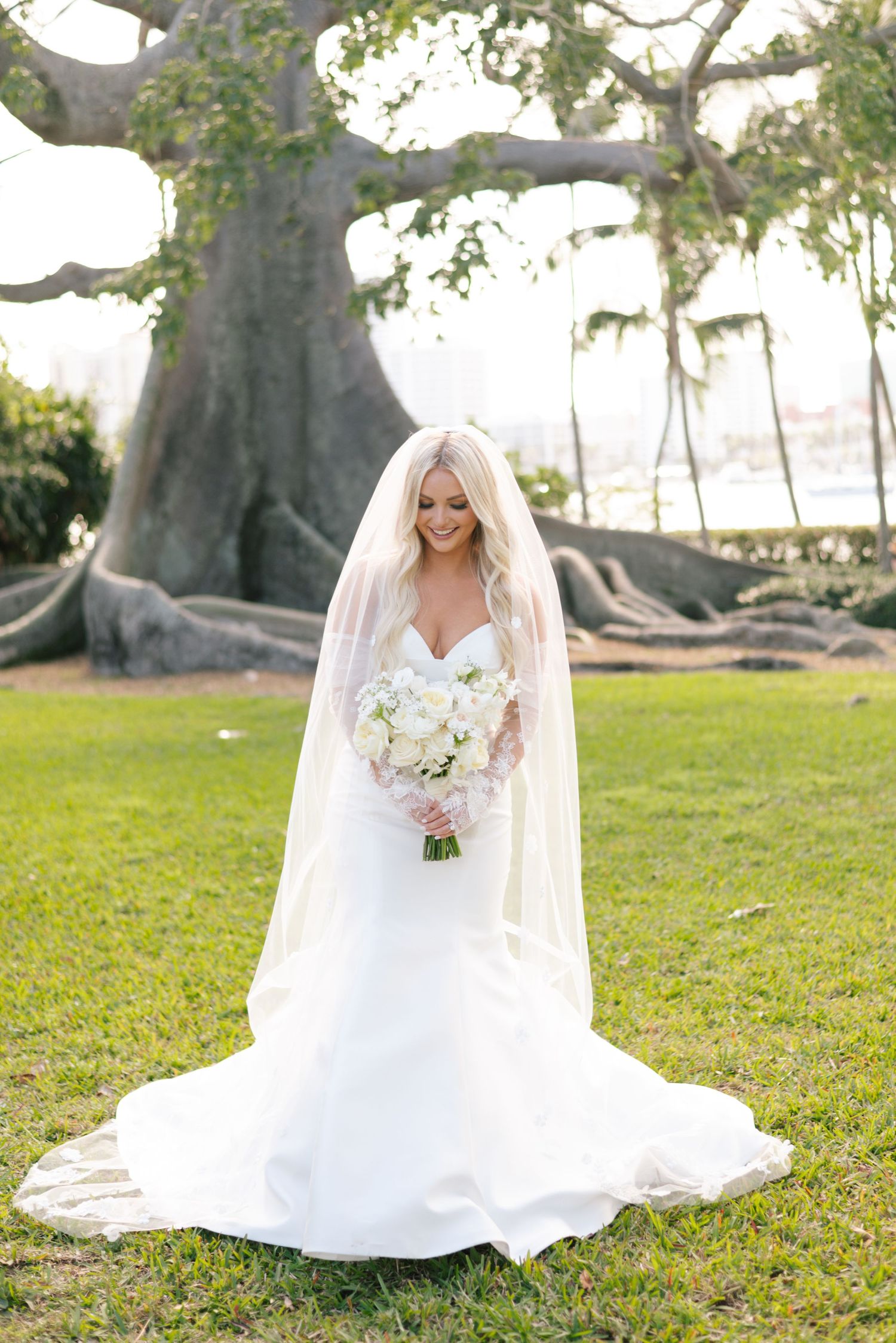 Elegant white wedding dress photographed in a garden setting with majestic oak trees in the background.