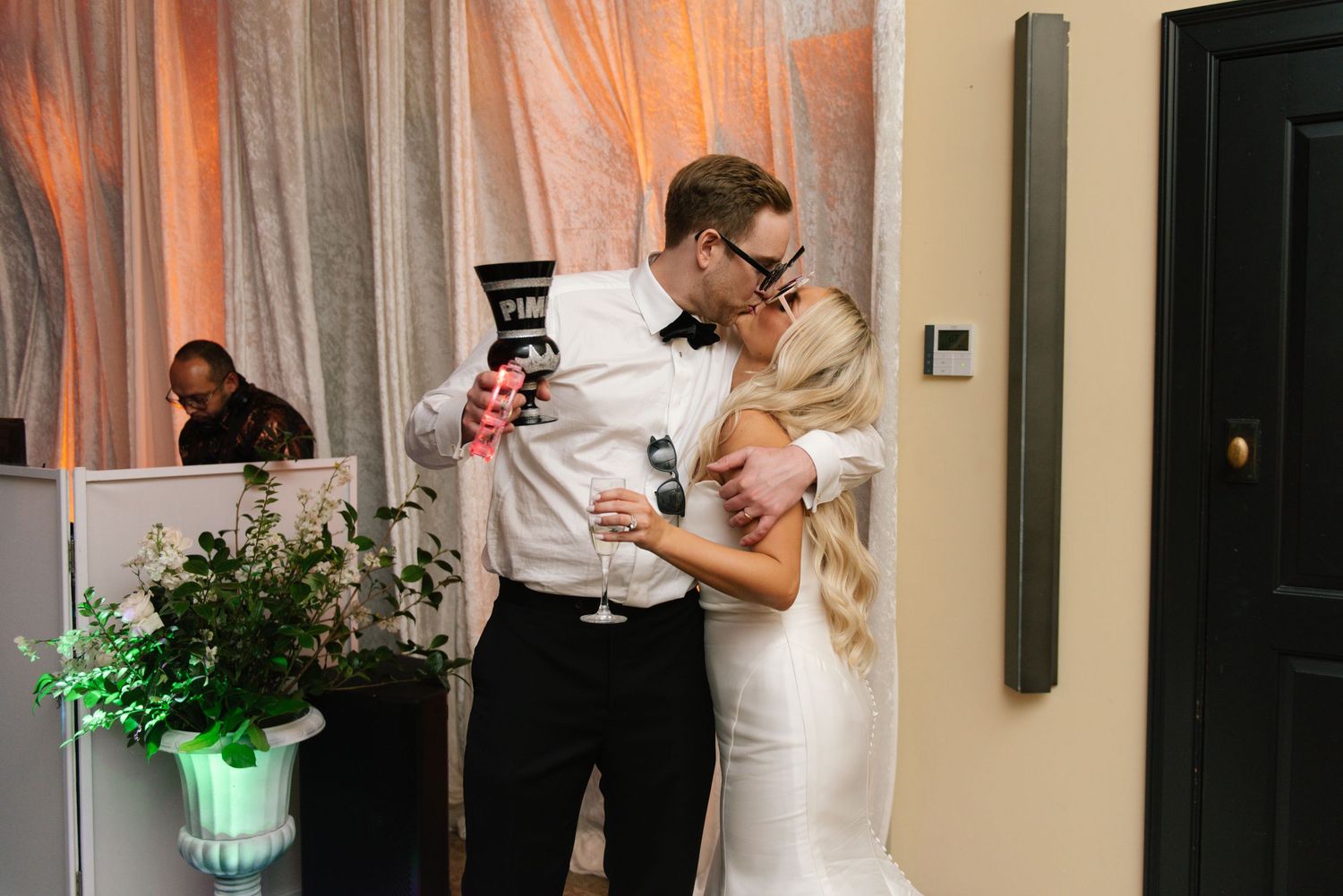 A wedding celebration in progress with guests mingling in a warmly lit indoor venue.
