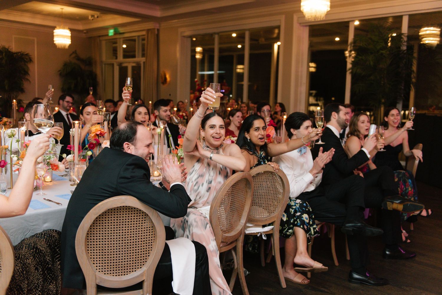 Wedding reception guests raising glasses in celebration at elegant dining venue.