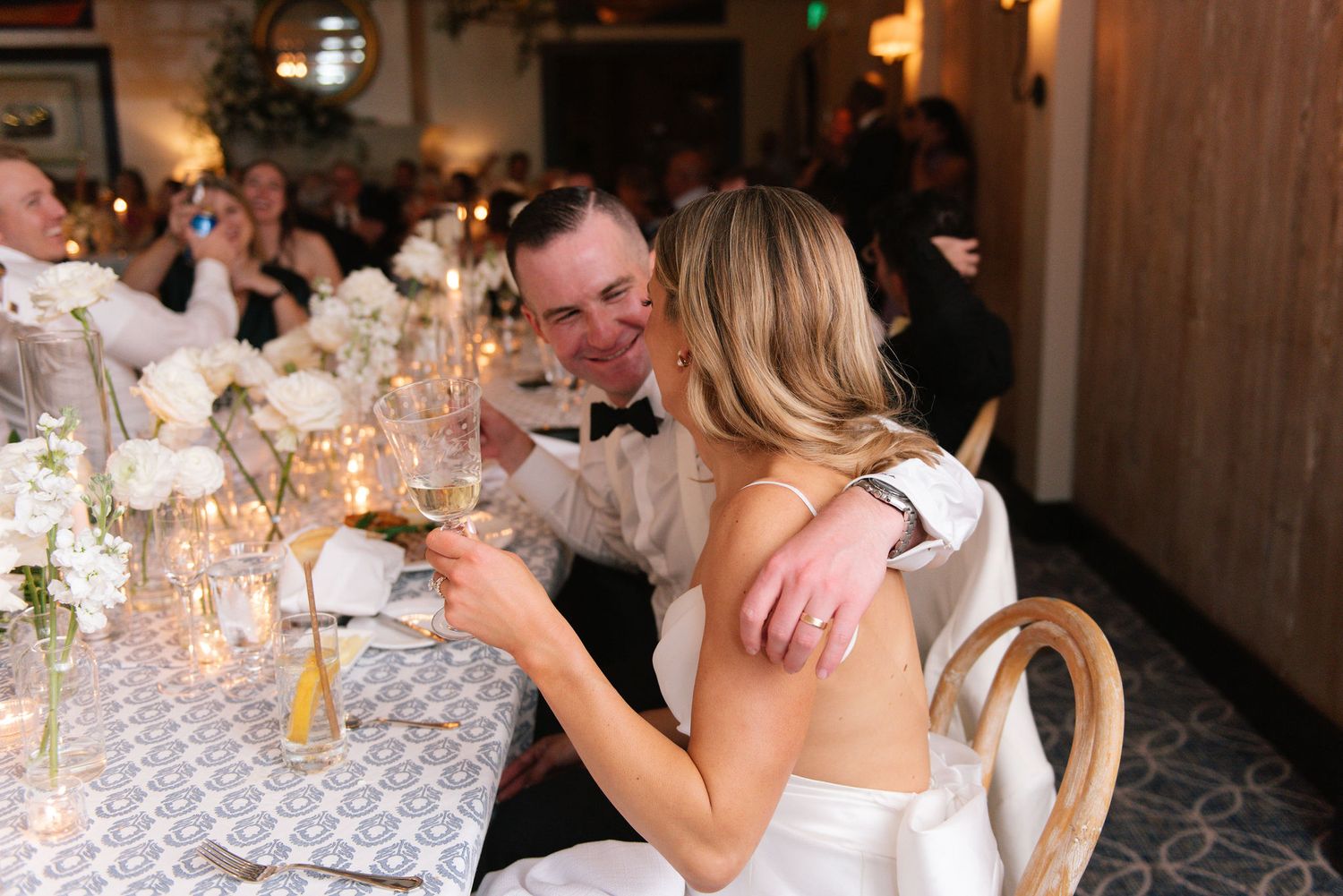 Elegant wedding reception tables decorated with glowing candles and floral centerpieces in a rustic venue.