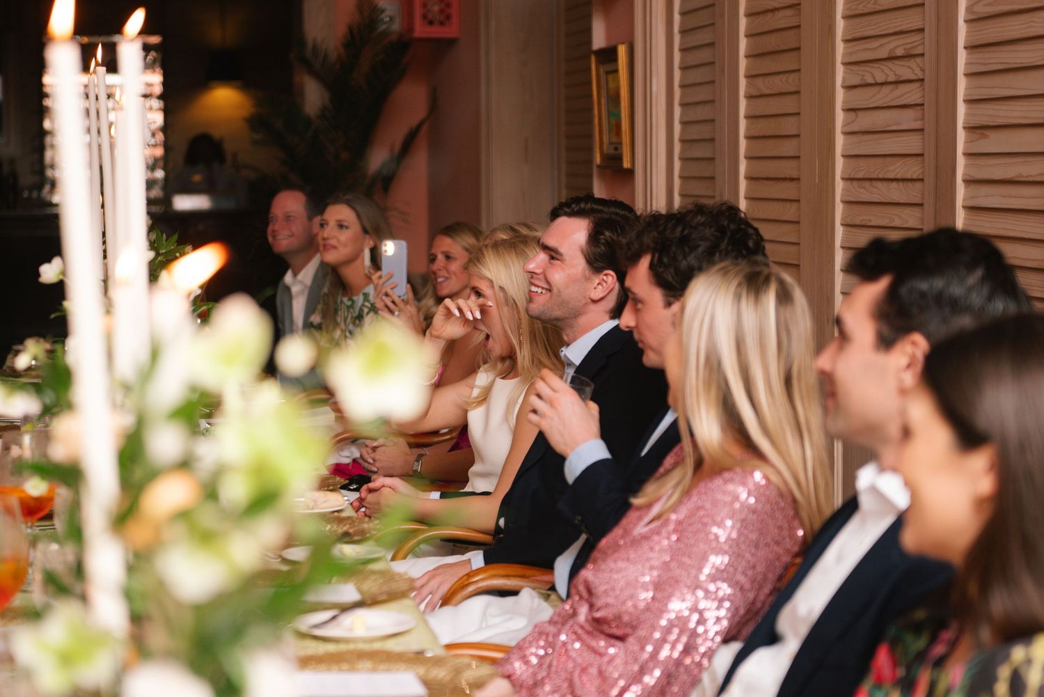 Group photo of wedding guests in coordinated pink and neutral outfits.