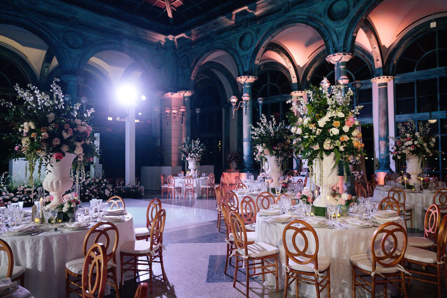 Elegant ballroom with classical columns and romantic lighting set for a formal evening event.