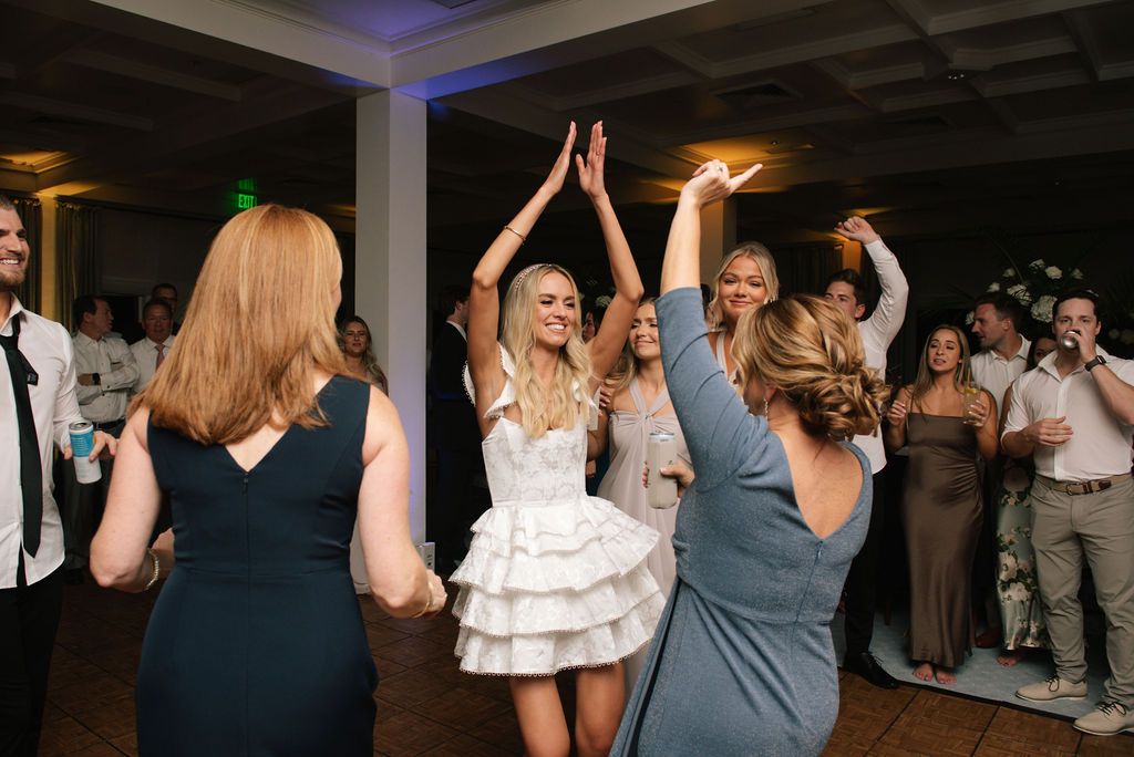 Party guests dance energetically on the dimly lit reception dance floor.