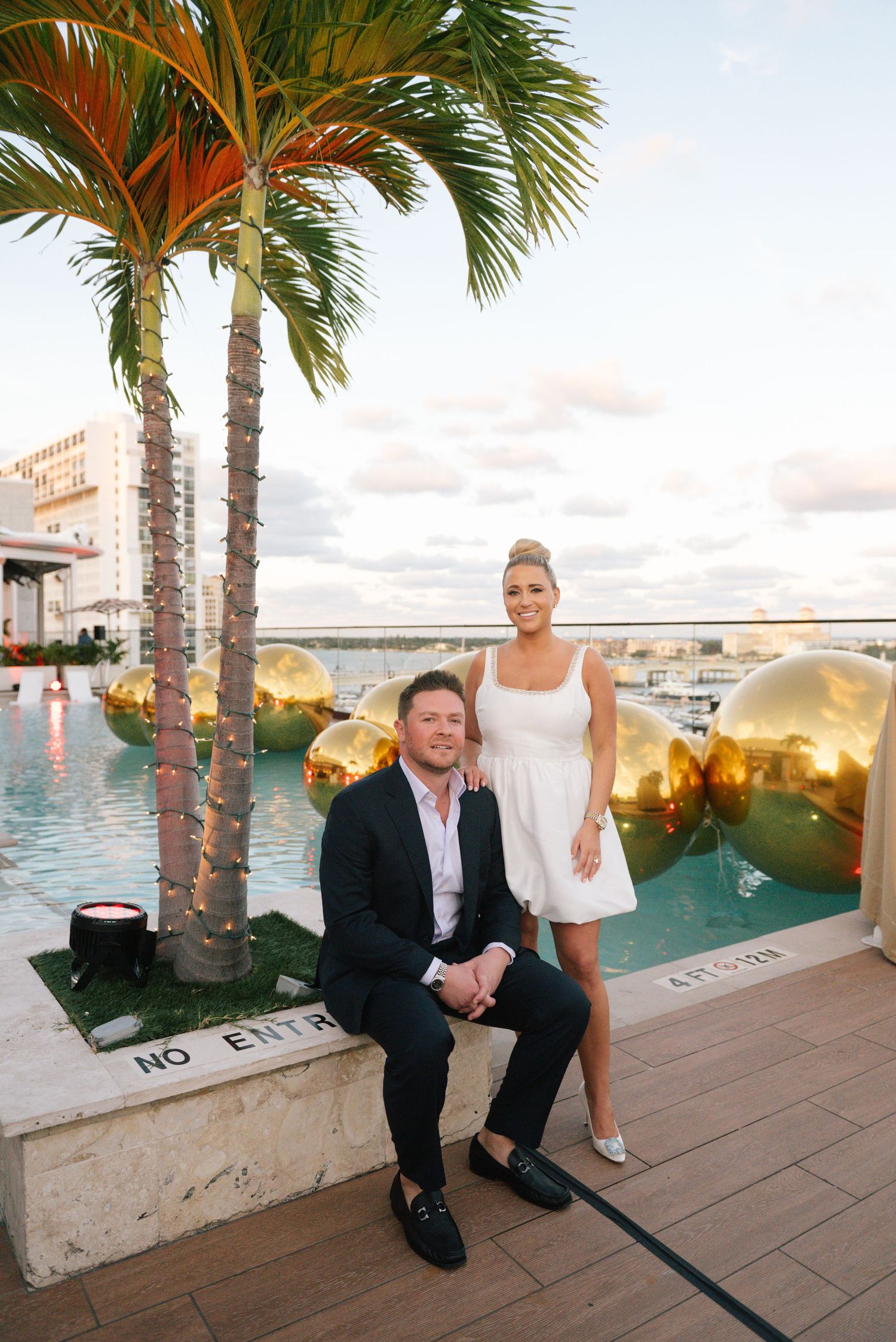 Waterfront venue with palm trees and seating area at sunset overlooking the ocean.