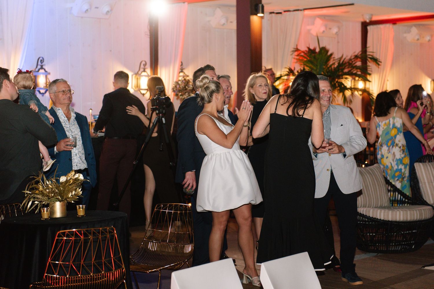 Indoor celebration with guests dancing under party lighting and decorative elements.